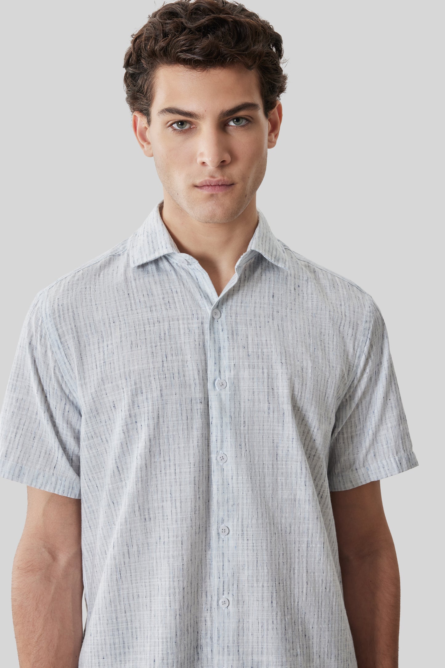 Man wearing light gray short-sleeve button-up shirt with textured weave pattern.