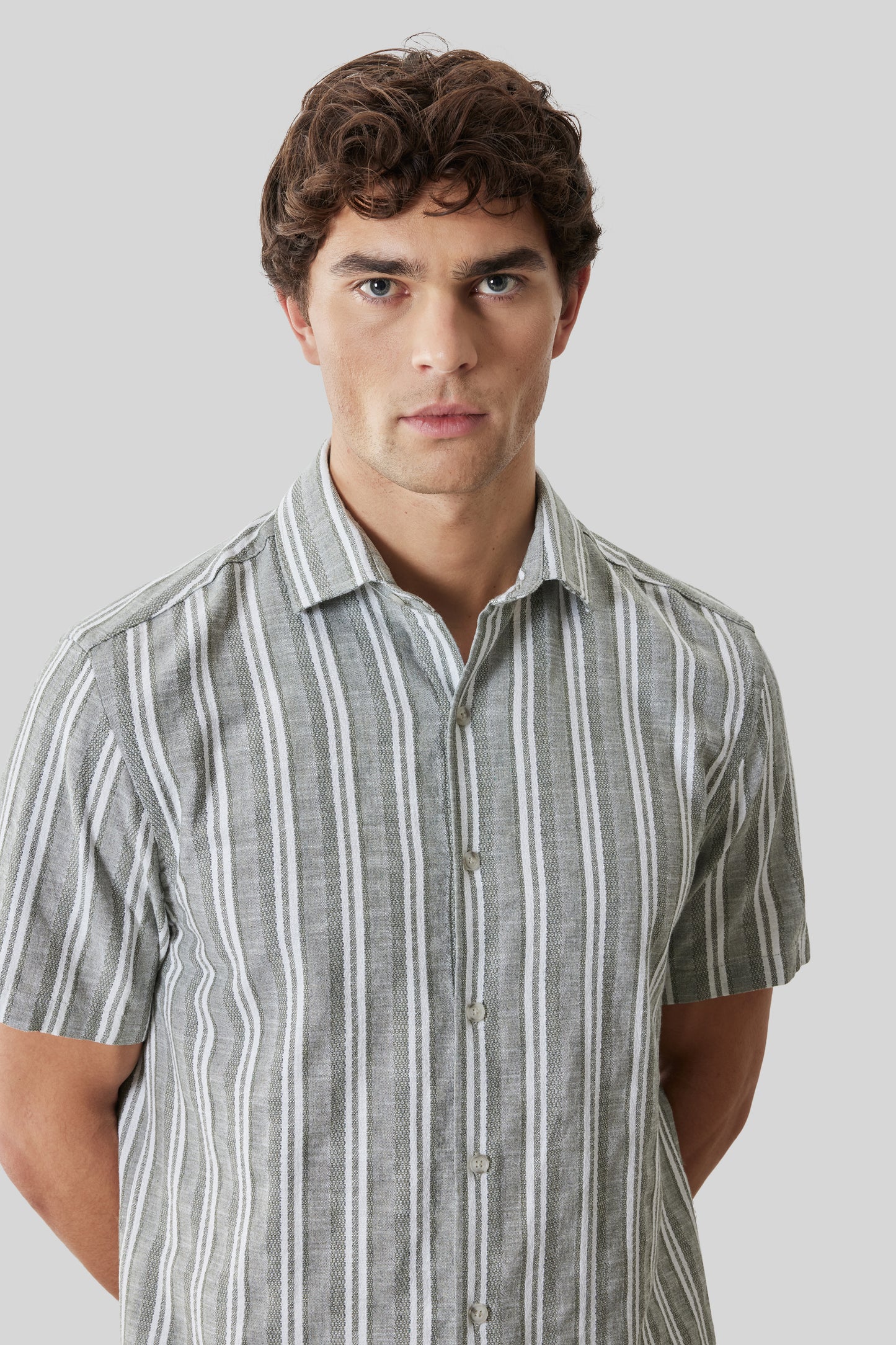 Man wearing a grey and white striped short sleeve button-up shirt.