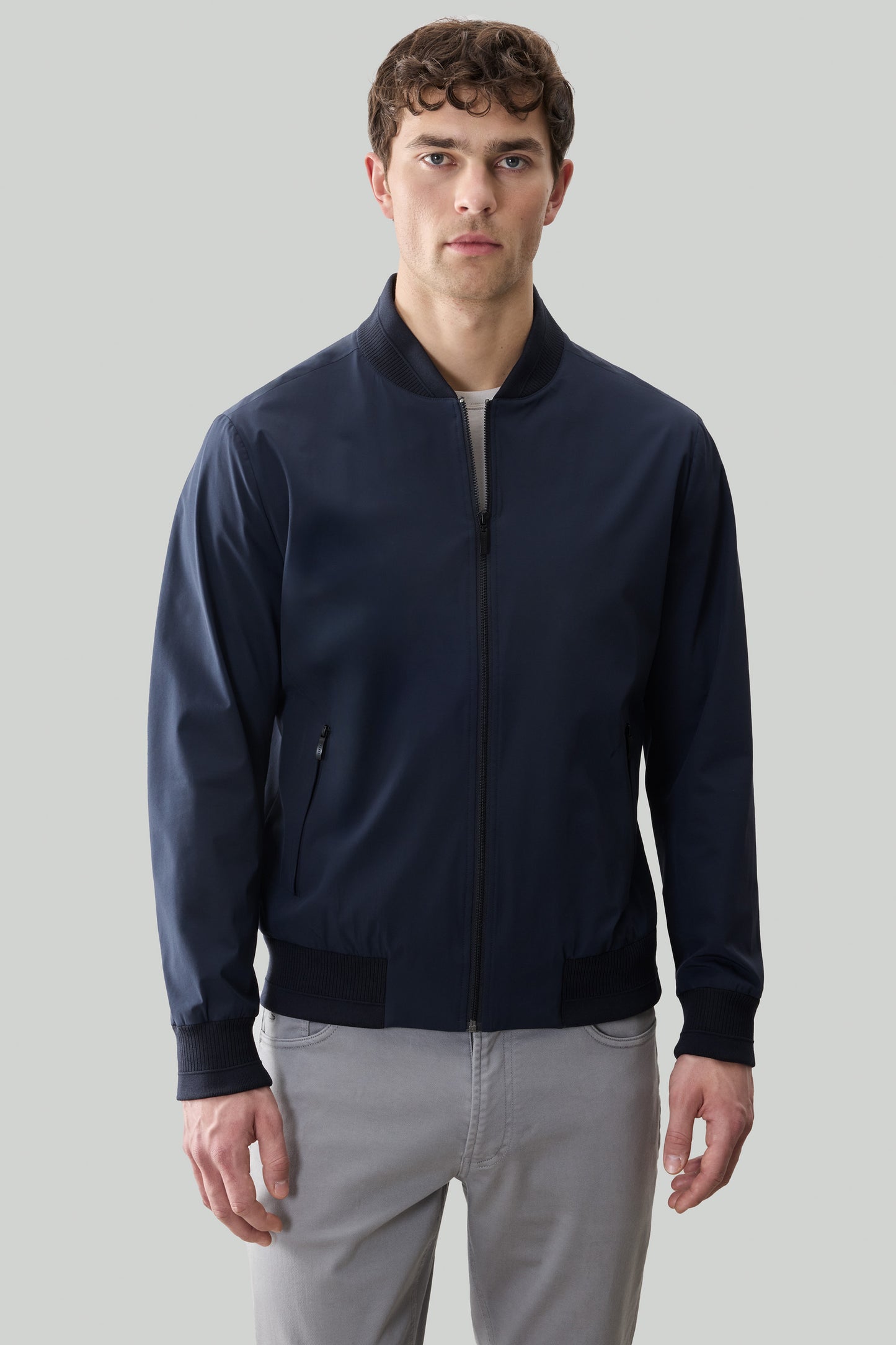 Navy blue bomber jacket with ribbed collar and cuffs, full-length zipper, and side pocket detail.