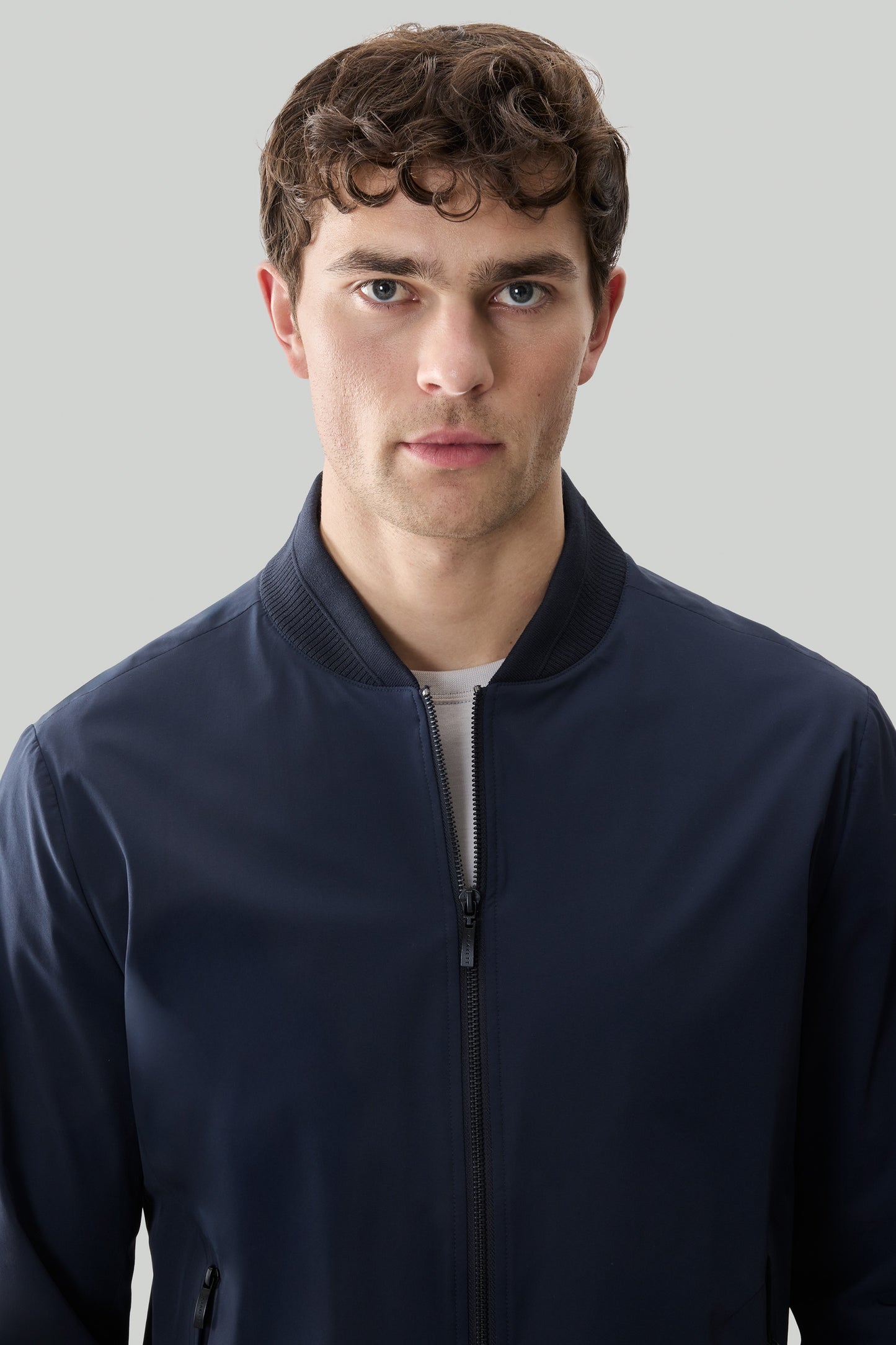Navy zip-up jacket with ribbed collar and cuffs worn by man against neutral background.