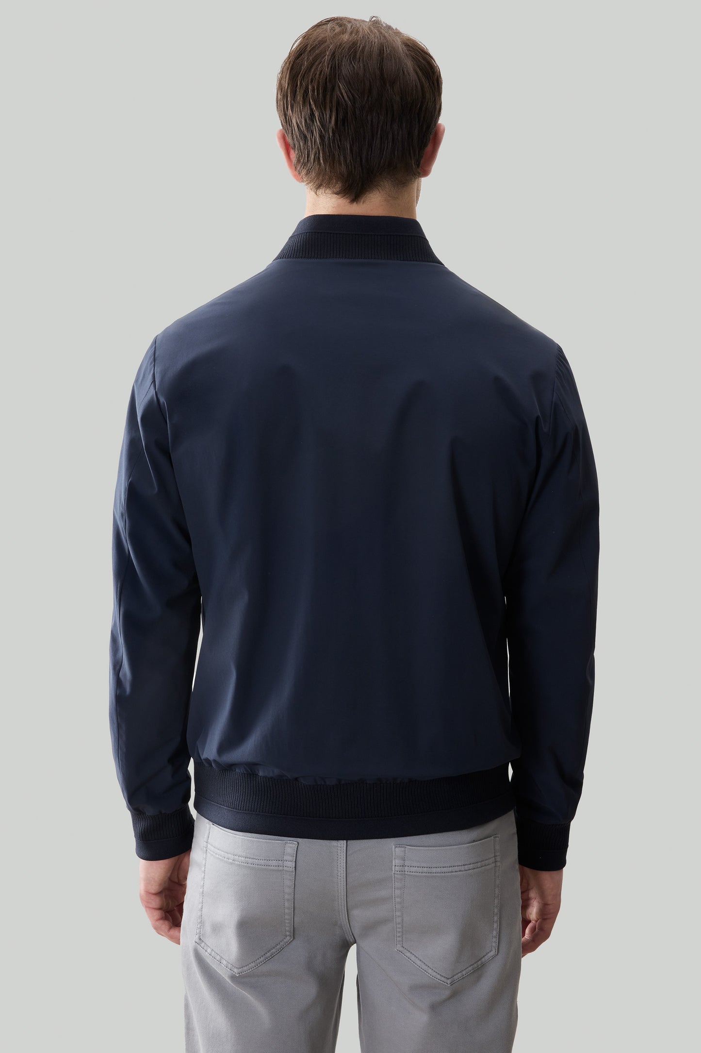 Navy blue bomber jacket with ribbed collar, cuffs, and hem, shown from back view on male model.