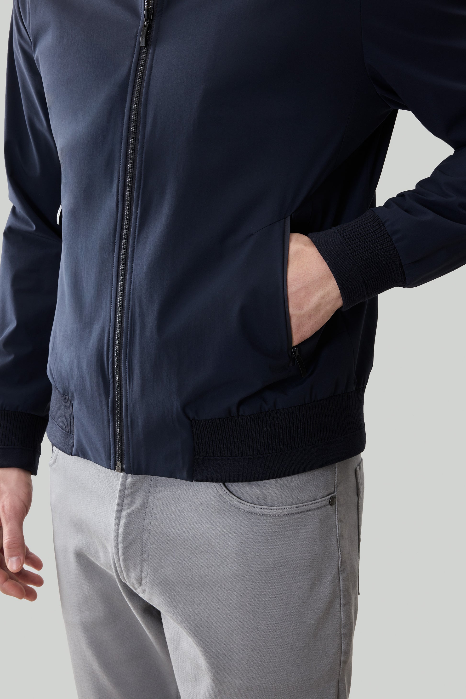 Navy blue jacket with full-length zipper, ribbed cuffs and hem, worn with gray pants.