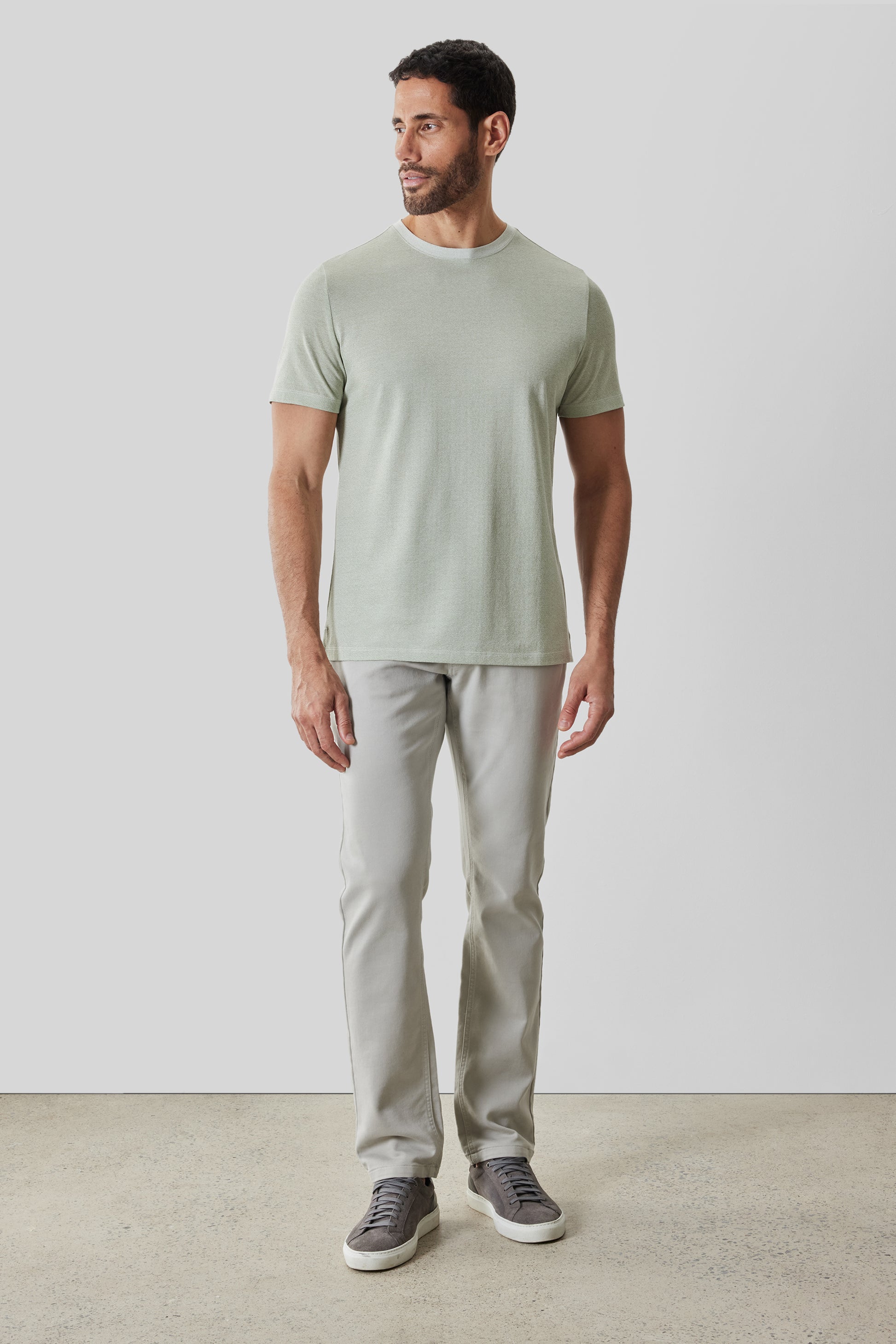 Man wearing sage green short-sleeve crew neck t-shirt and light gray pants with dark sneakers.