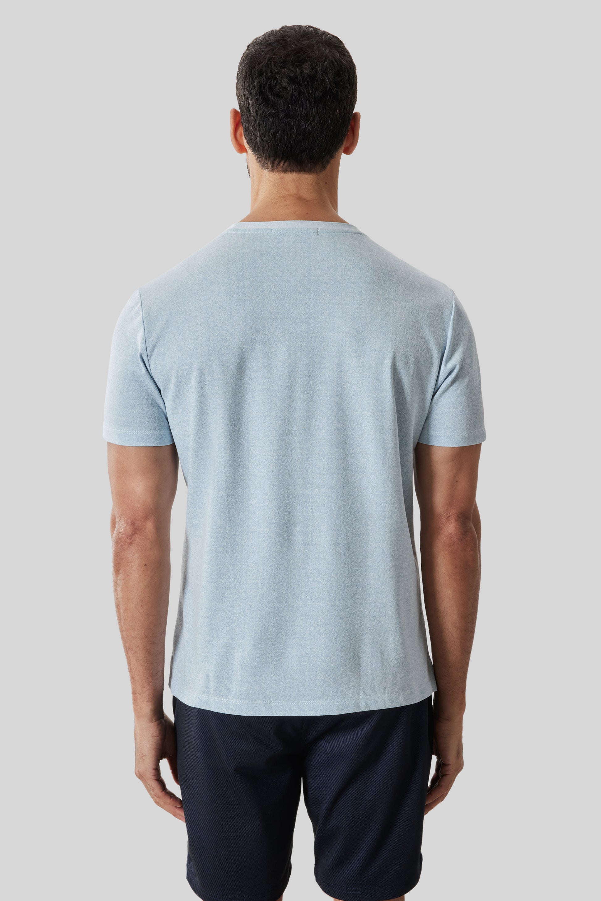 Man wearing light blue short-sleeve t-shirt with crew neckline, shown from back view.
