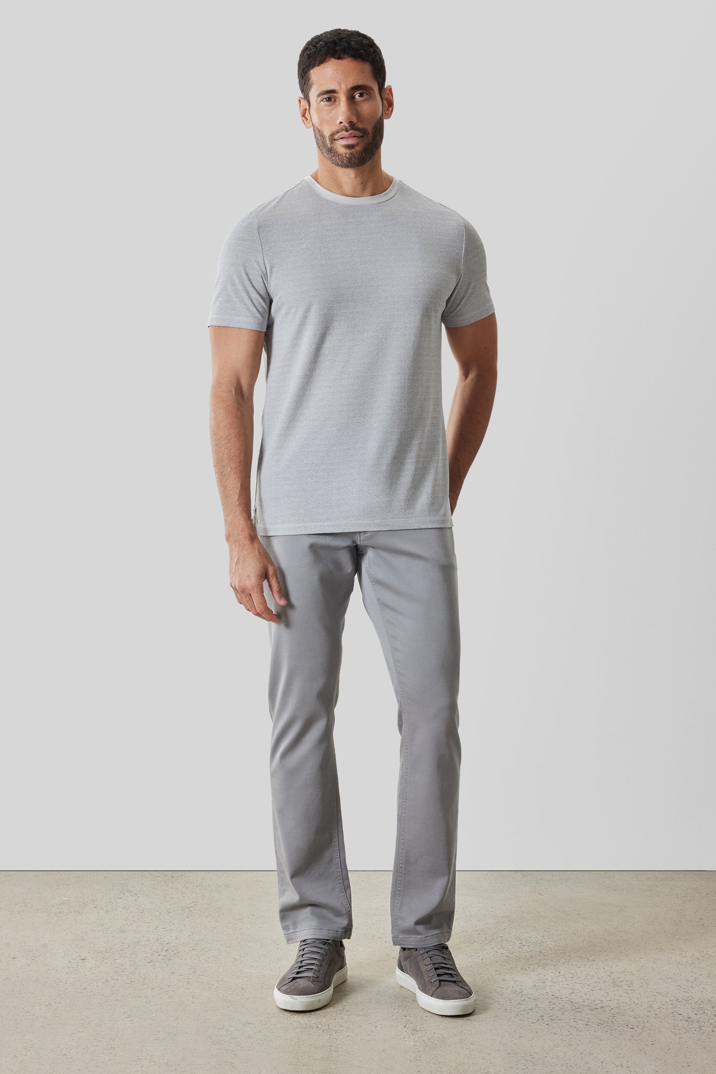Man wearing light gray short-sleeve crew neck t-shirt with gray pants and dark sneakers.