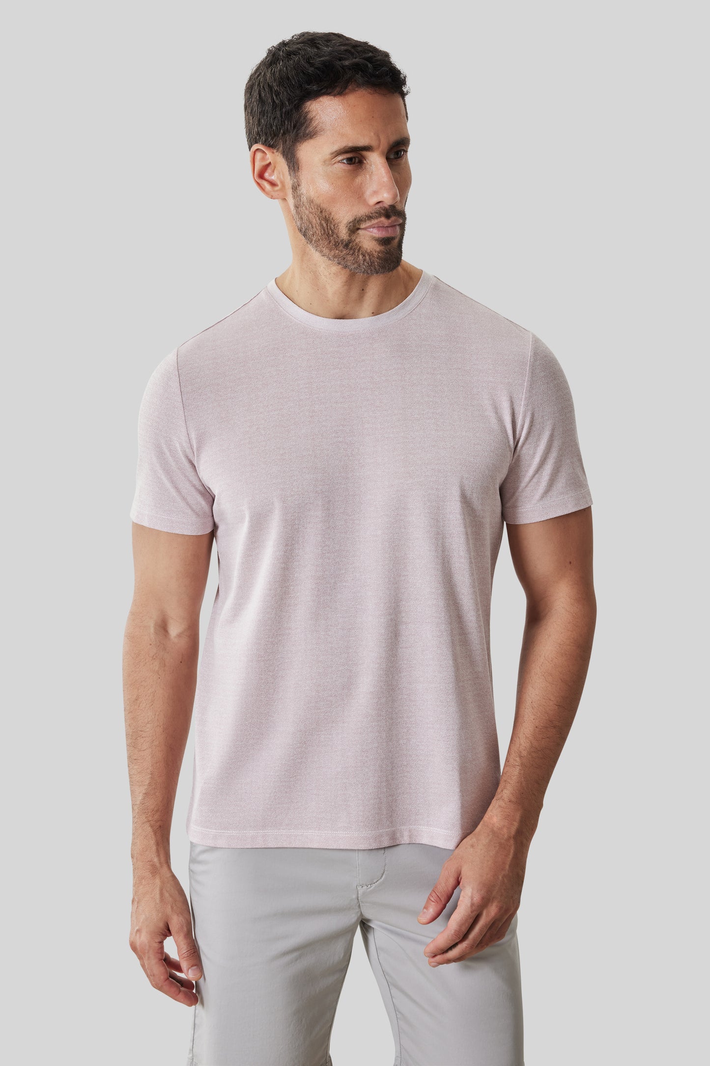 Man wearing light pink short-sleeve crew neck tee with light gray pants.