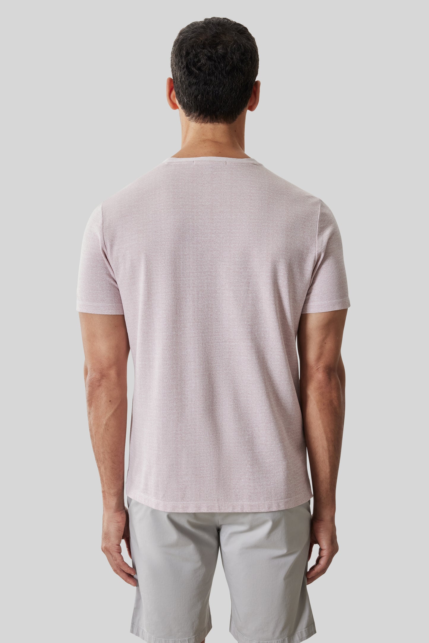 Man wearing light pink short-sleeve t-shirt with crew neckline, shown from back view.