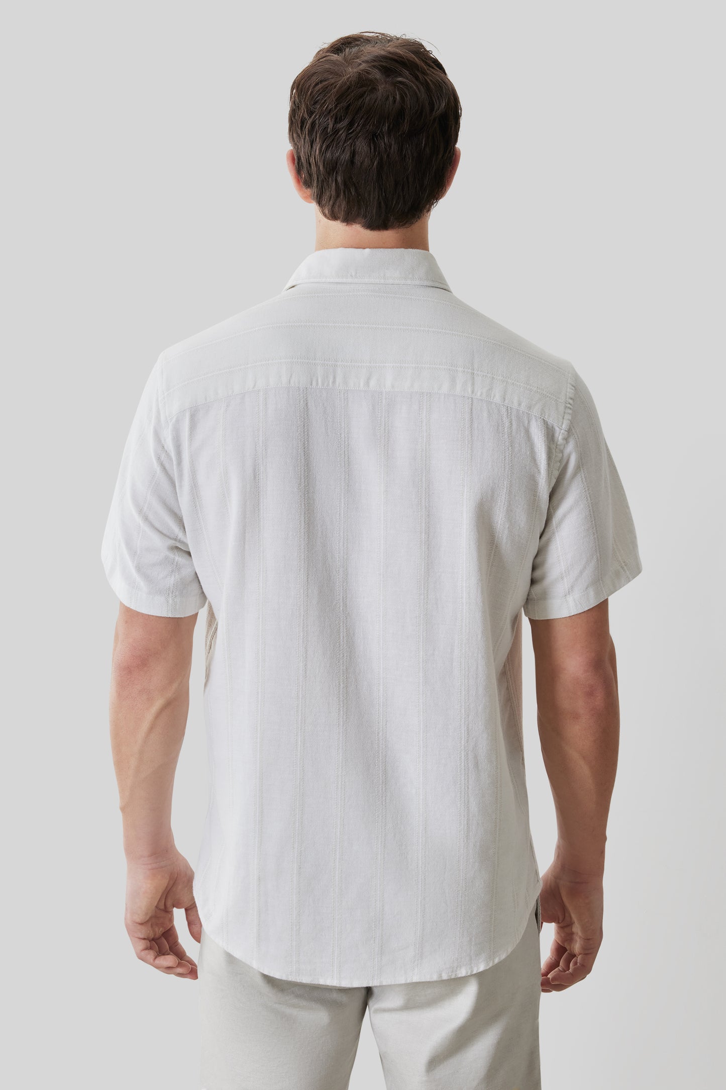 White short sleeve button-up shirt with collar, shown on male model from back view.
