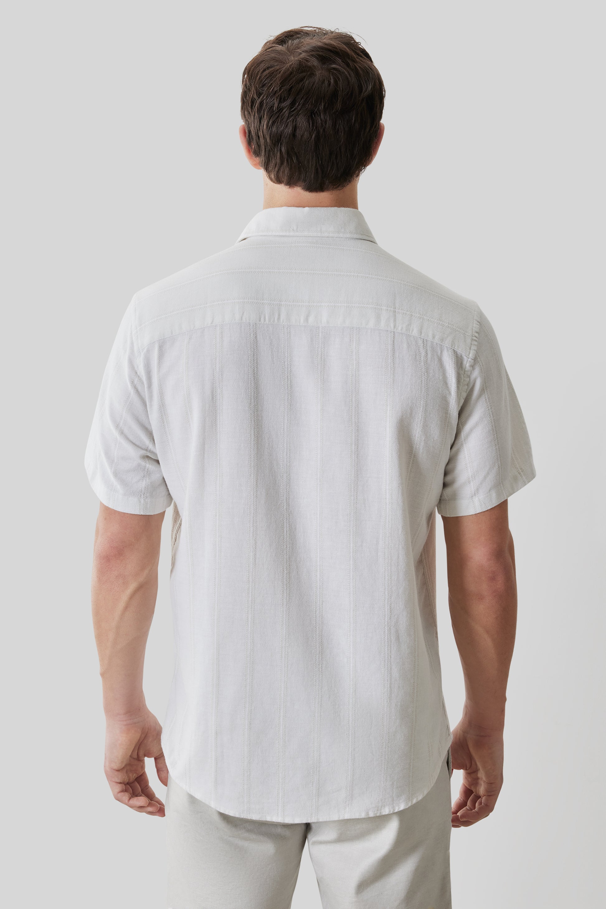 White short sleeve button-up shirt with collar, shown on male model from back view.
