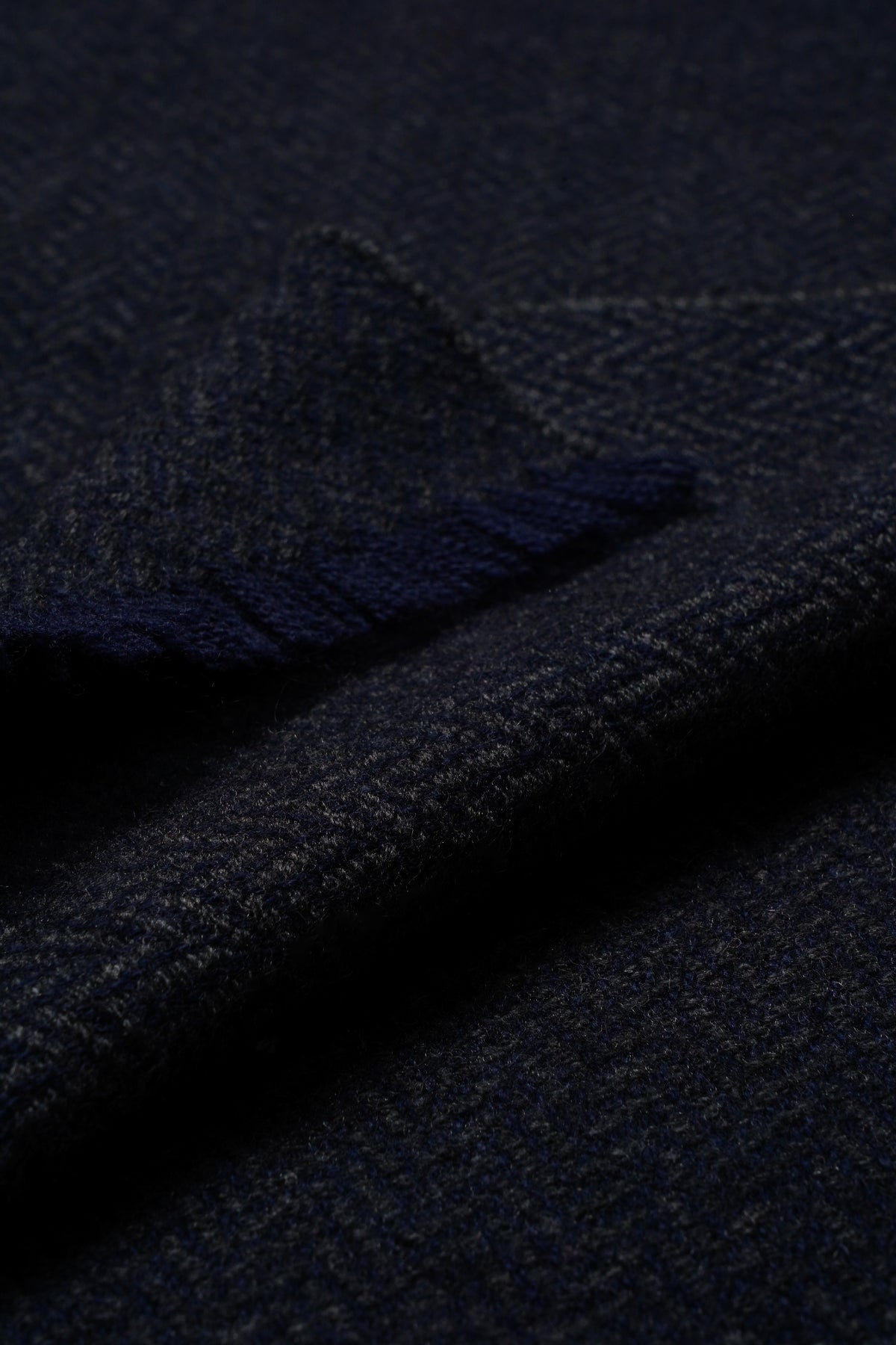 Dark navy cashmere scarf with soft, textured weave shown folded to display fabric detail and surface quality.