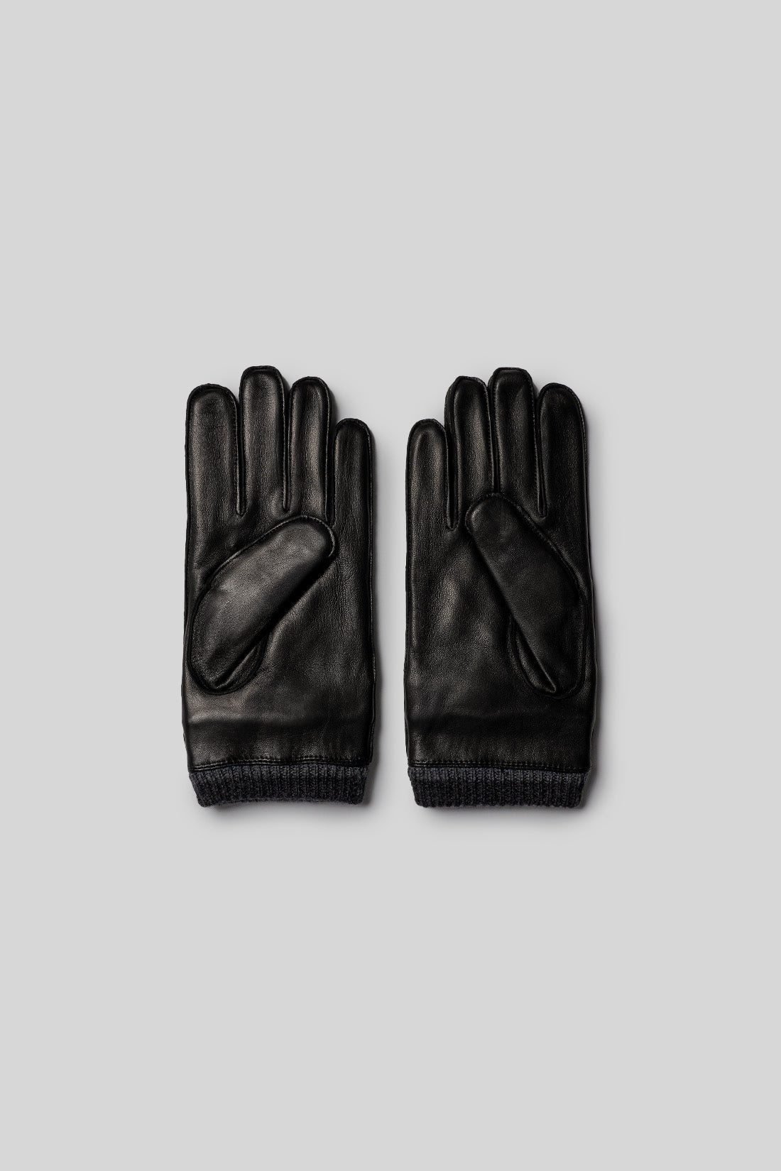 Black leather gloves with ribbed wrist cuffs, displayed flat on a neutral background.