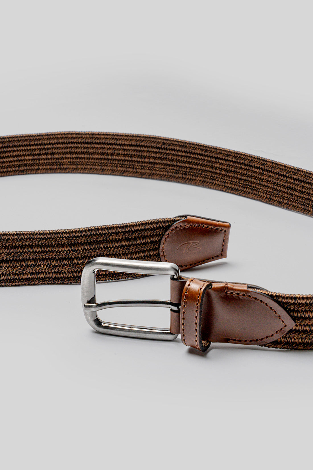 Brown woven fabric belt with brown leather trim and silver-toned metal buckle.