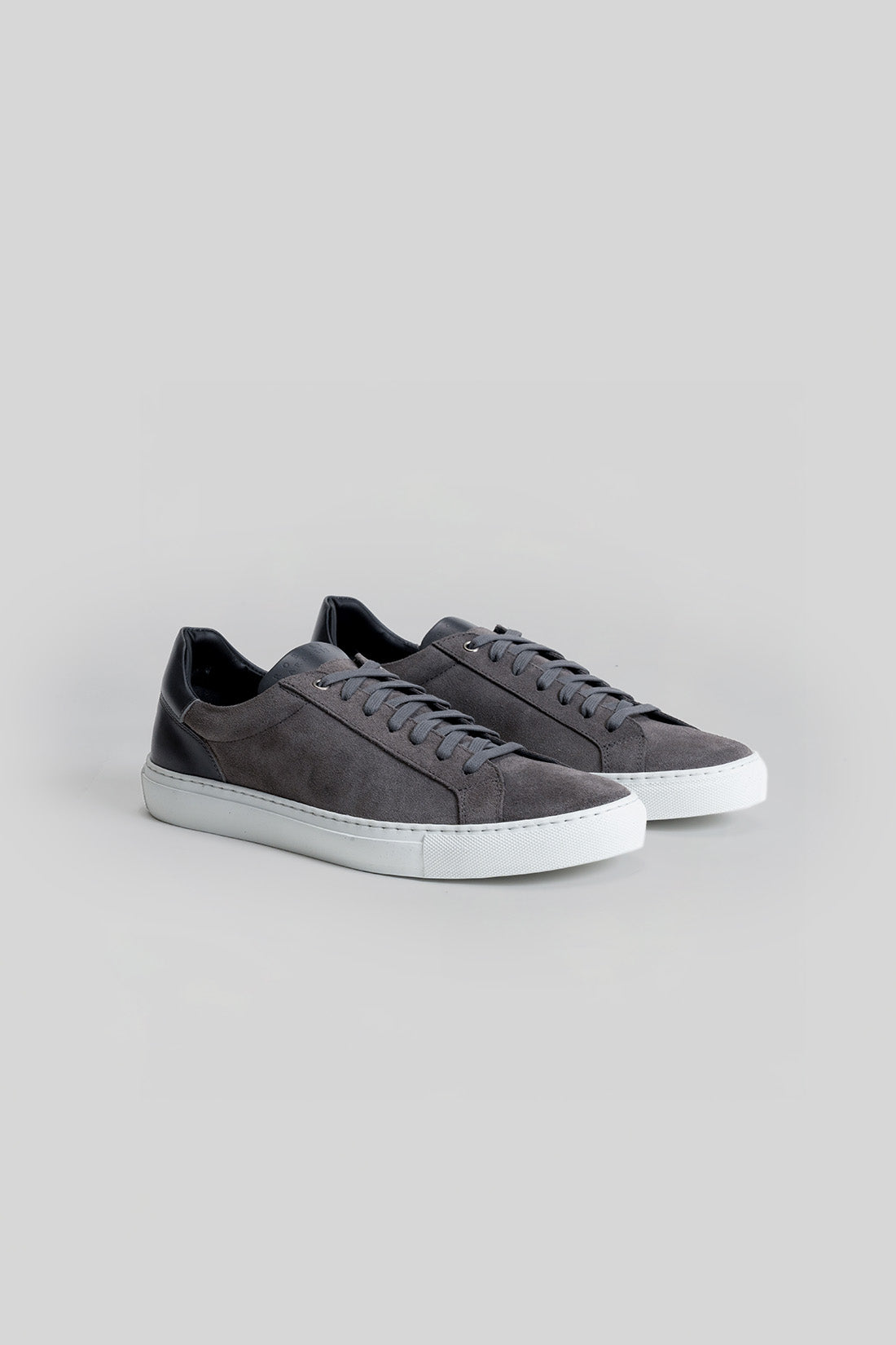 Gray suede sneakers with white rubber sole and black heel counter, shown as a pair from the side angle.