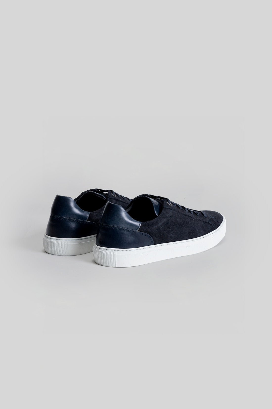 Navy and black sneaker with white rubber sole, shown from rear three-quarter view.