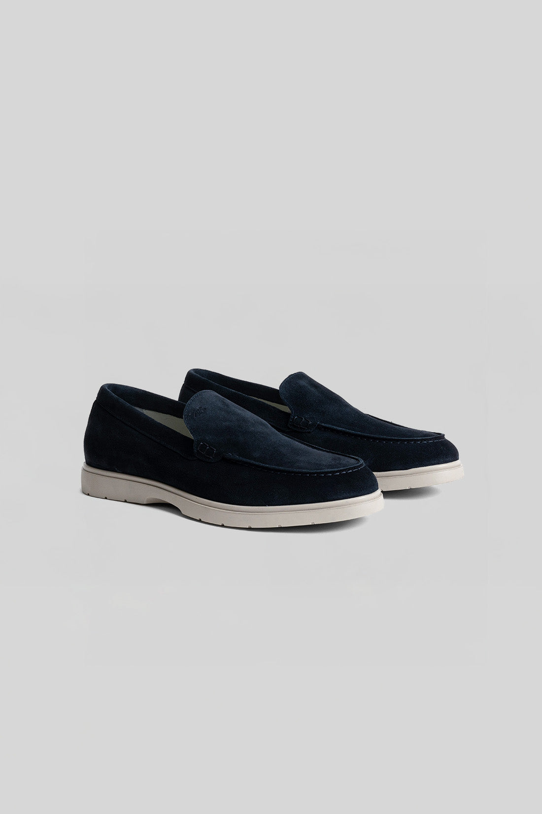 Pair of navy suede loafers with white rubber soles, shown from the side.