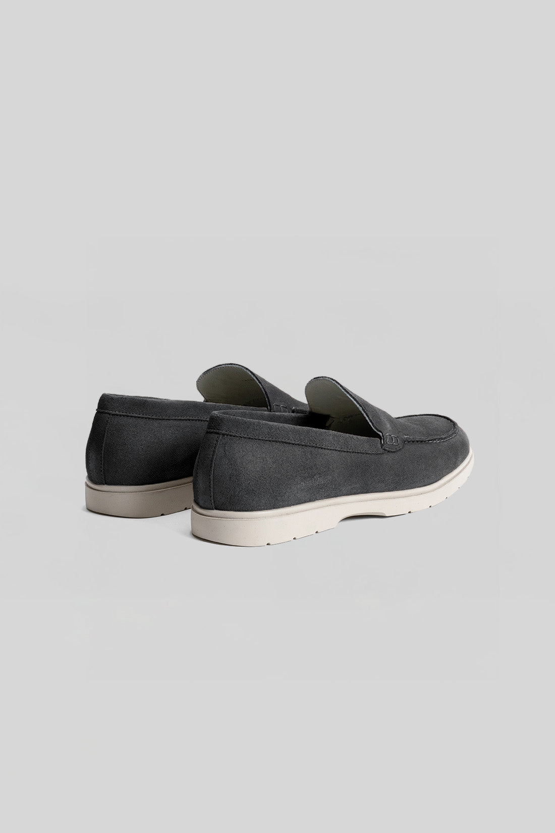 Dark gray suede loafers with white crepe sole, shown from the back three-quarter view.