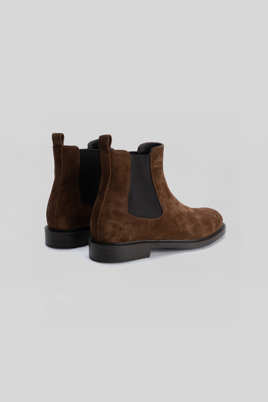 Brown suede Chelsea boot with black elastic side panels and black sole, shown from rear three-quarter view.