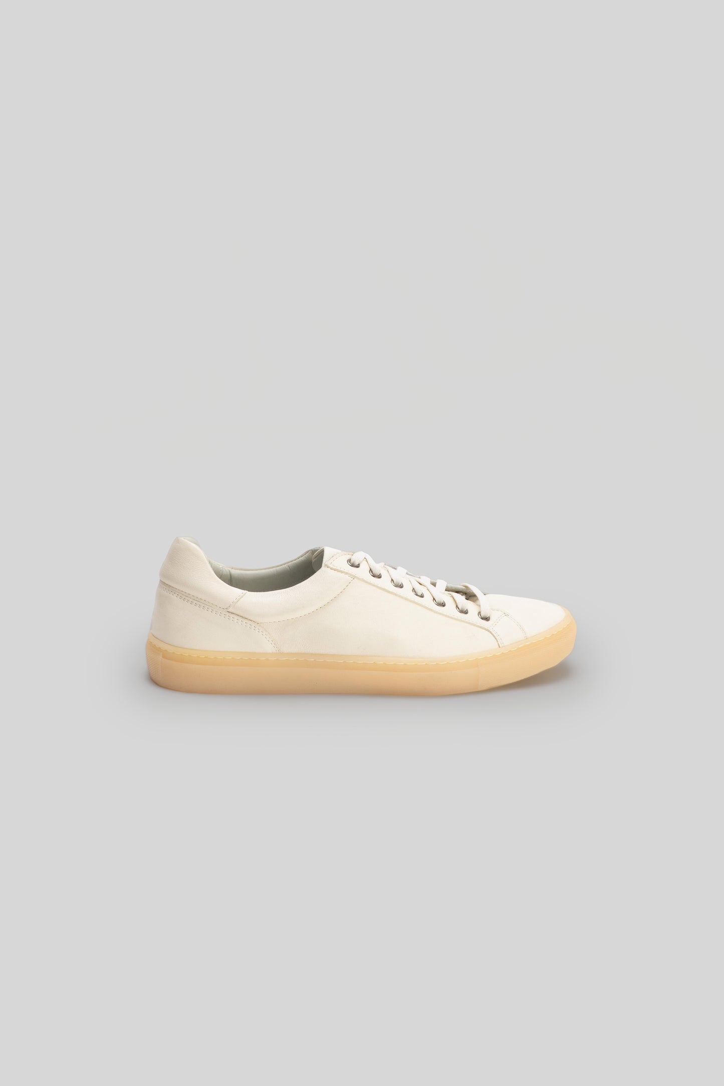 Cream leather low-top sneaker with cream laces and tan rubber sole, shown in profile view.