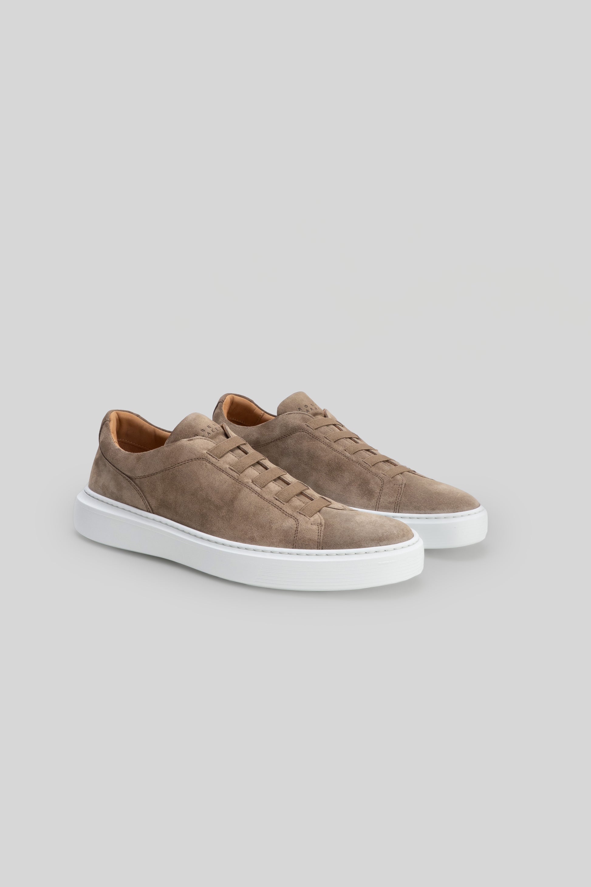 Pair of beige suede sneakers with white rubber soles and elastic lace detailing on the vamp.