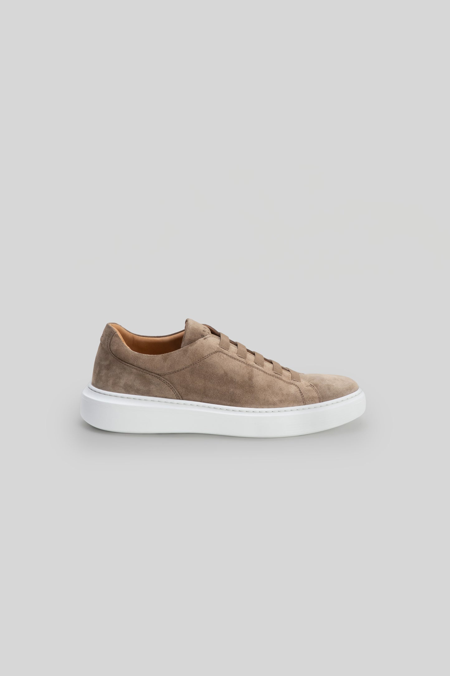 Taupe suede sneaker with elastic lacing and white sole, shown in side profile.