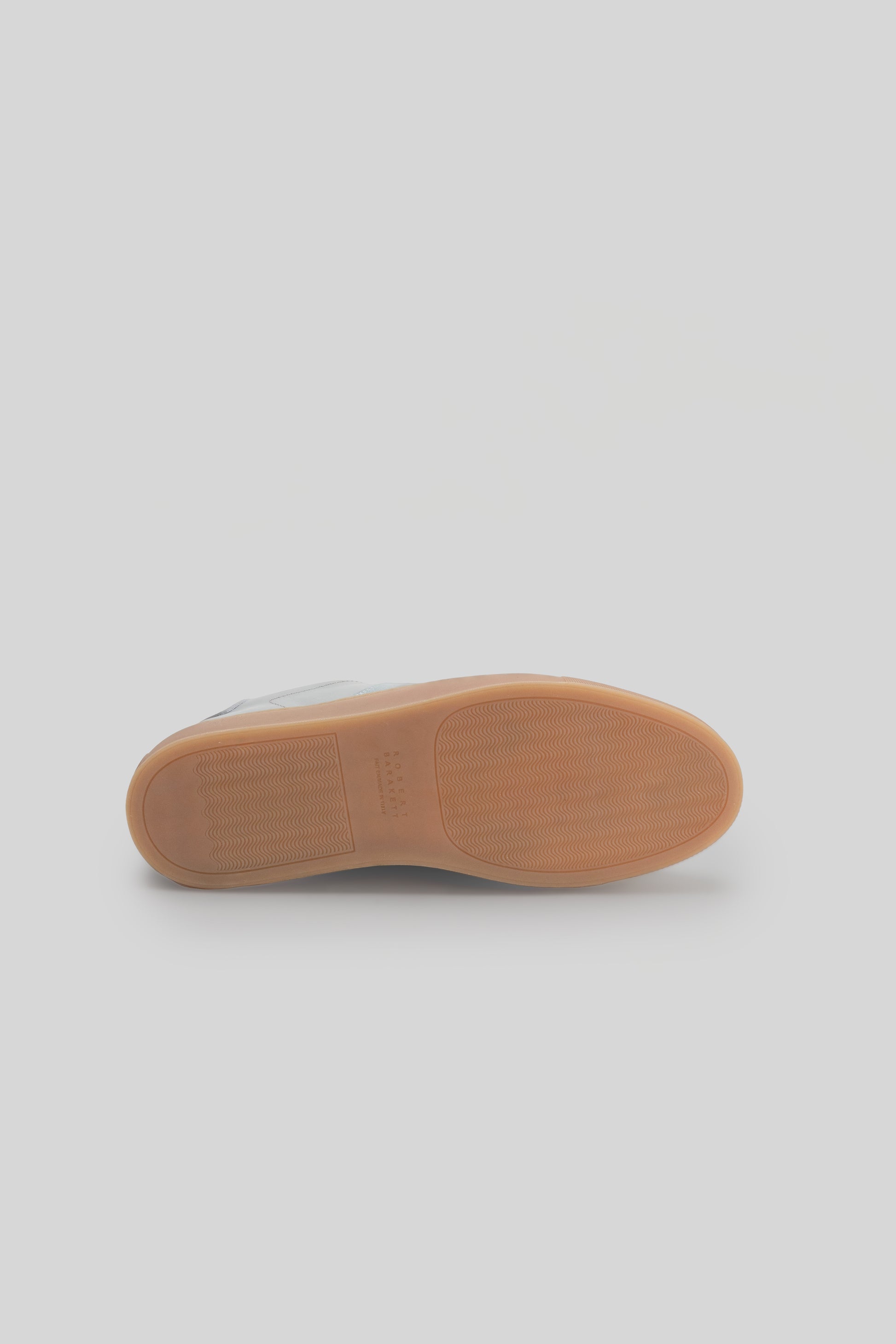 Tan rubber sole of a low-top sneaker with textured surface and curved profile.