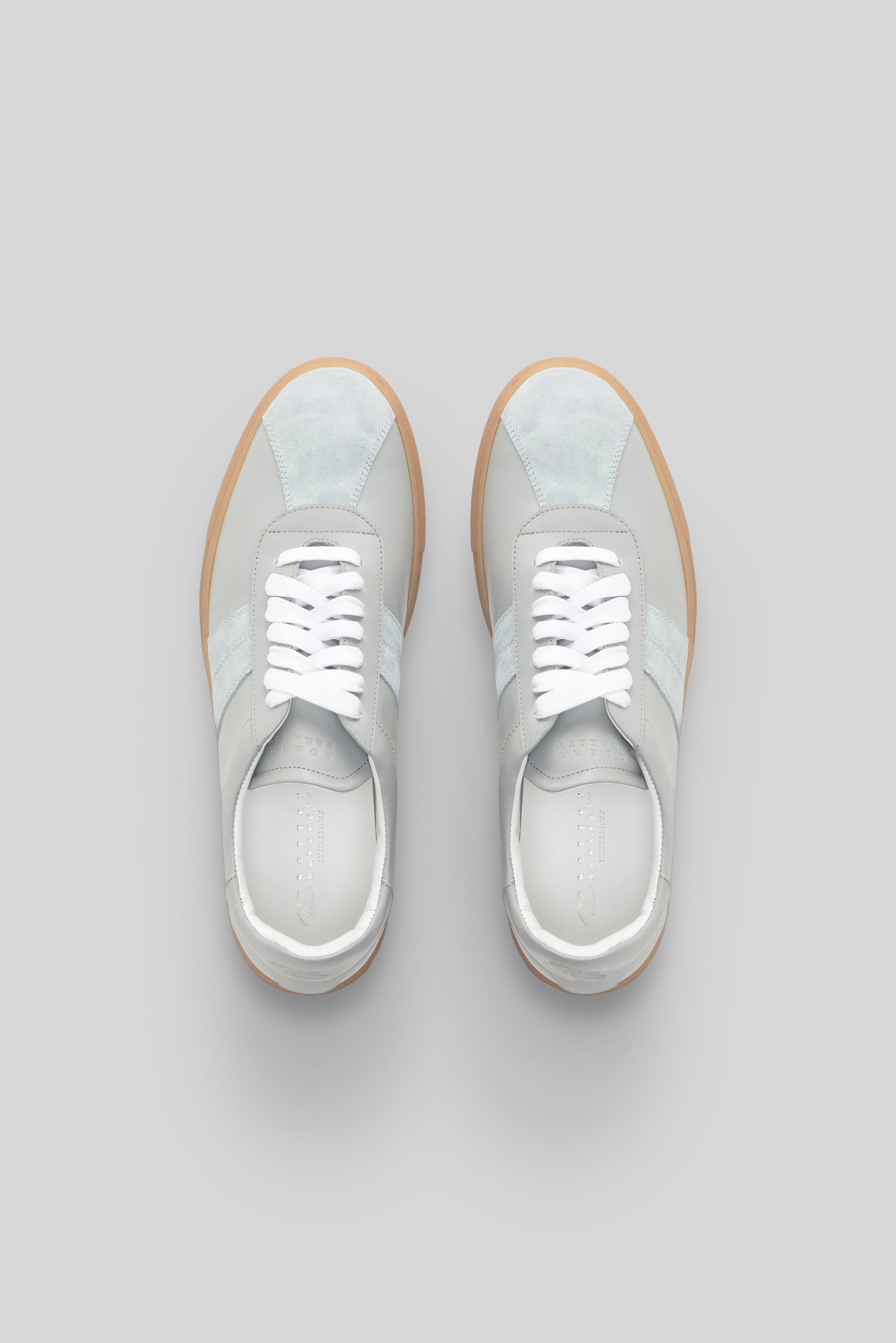 White and gray striped sneakers with white laces and tan rubber sole, shown from above.