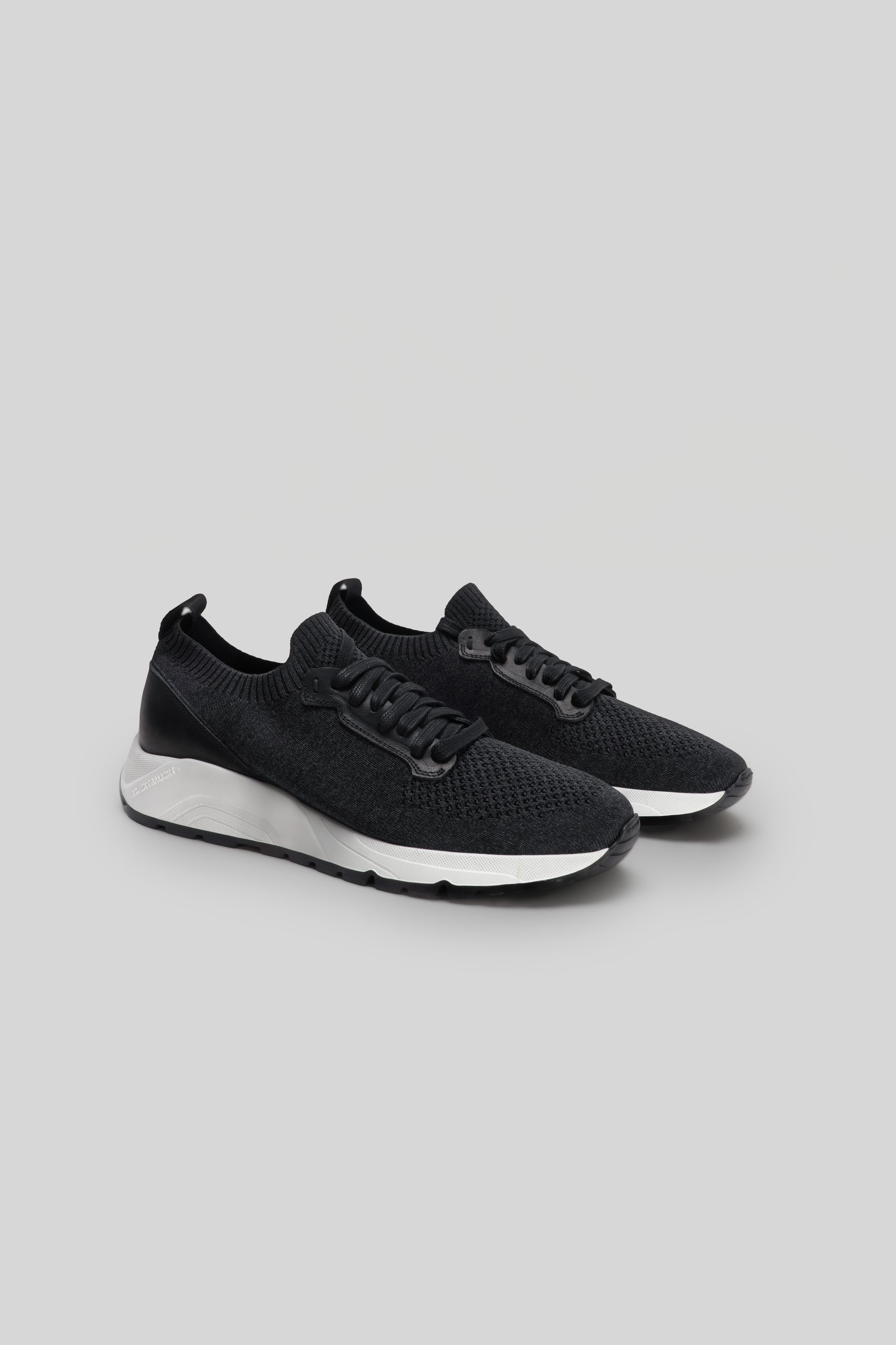 Black knit sneakers with white sole and black laces, shown from the side.