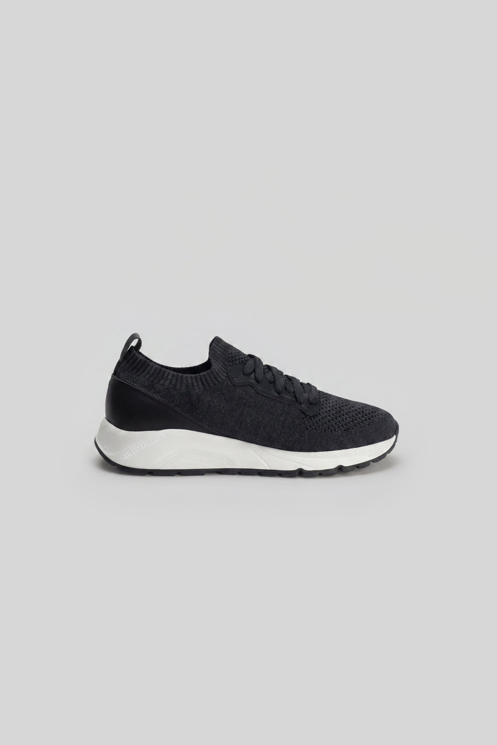Black knit sneaker with white sole and lace-up closure, shown in side profile.