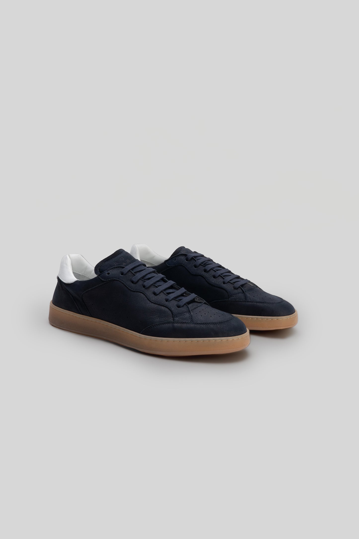 Black suede sneaker with white heel collar and tan rubber sole, shown from the side.