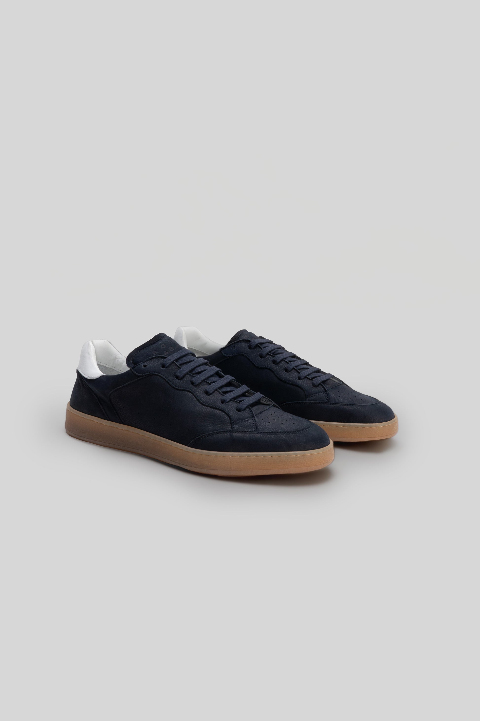 Black suede sneaker with white heel collar and tan rubber sole, shown from the side.