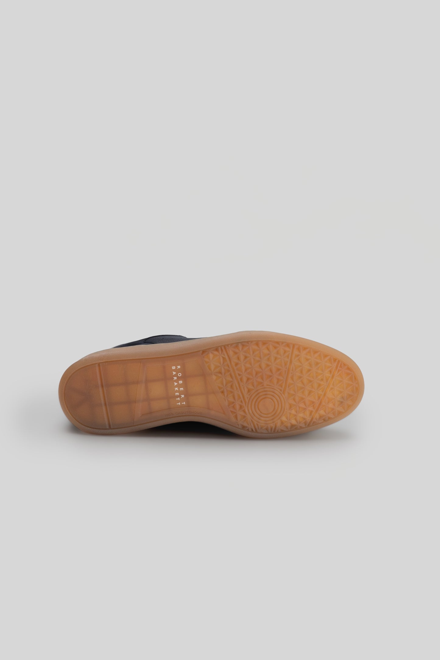 Navy leather sneaker with tan rubber sole featuring textured tread pattern, shown from underside view.