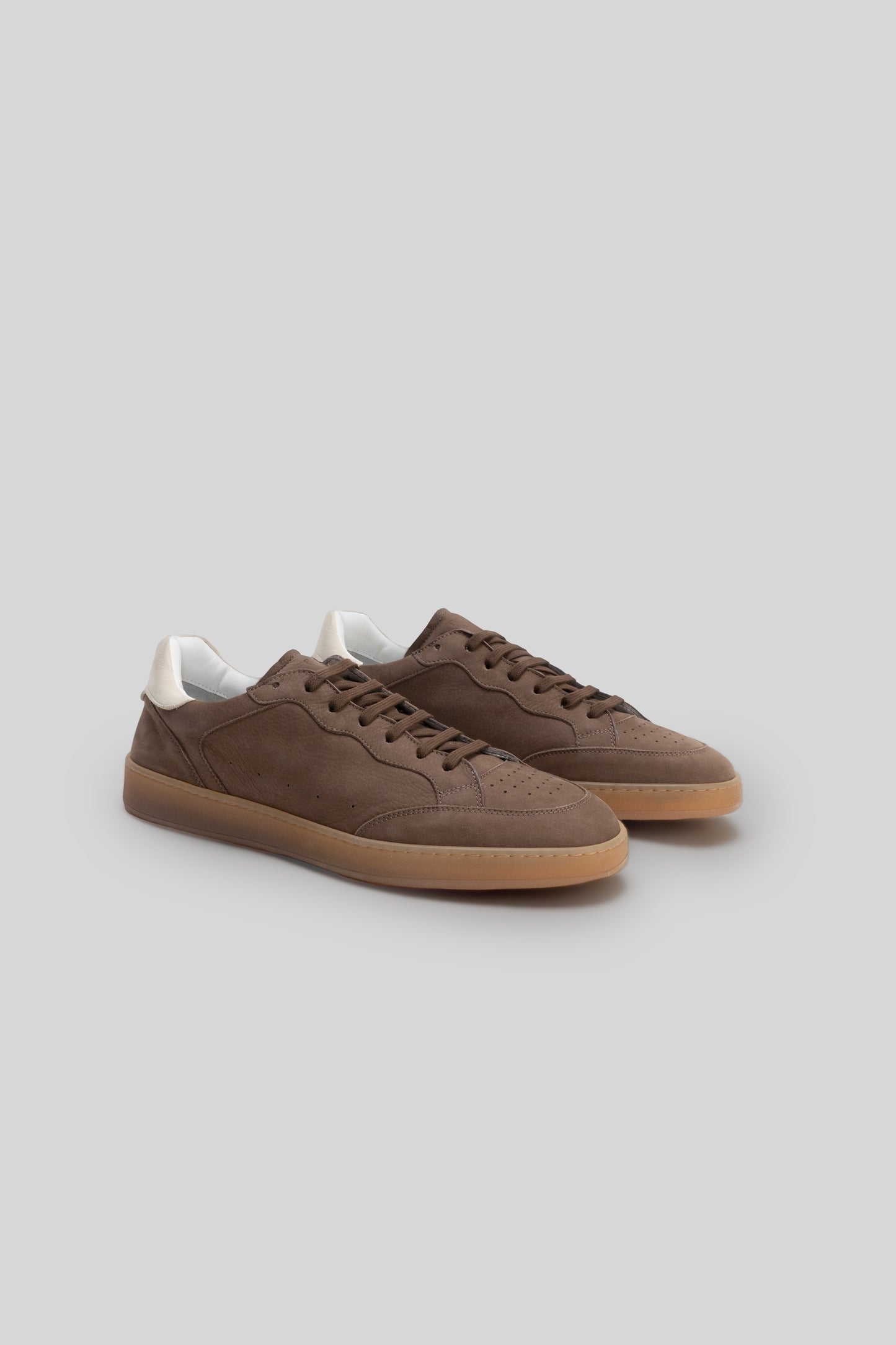 Brown suede sneakers with white collar trim and gum rubber sole, shown in three-quarter view.