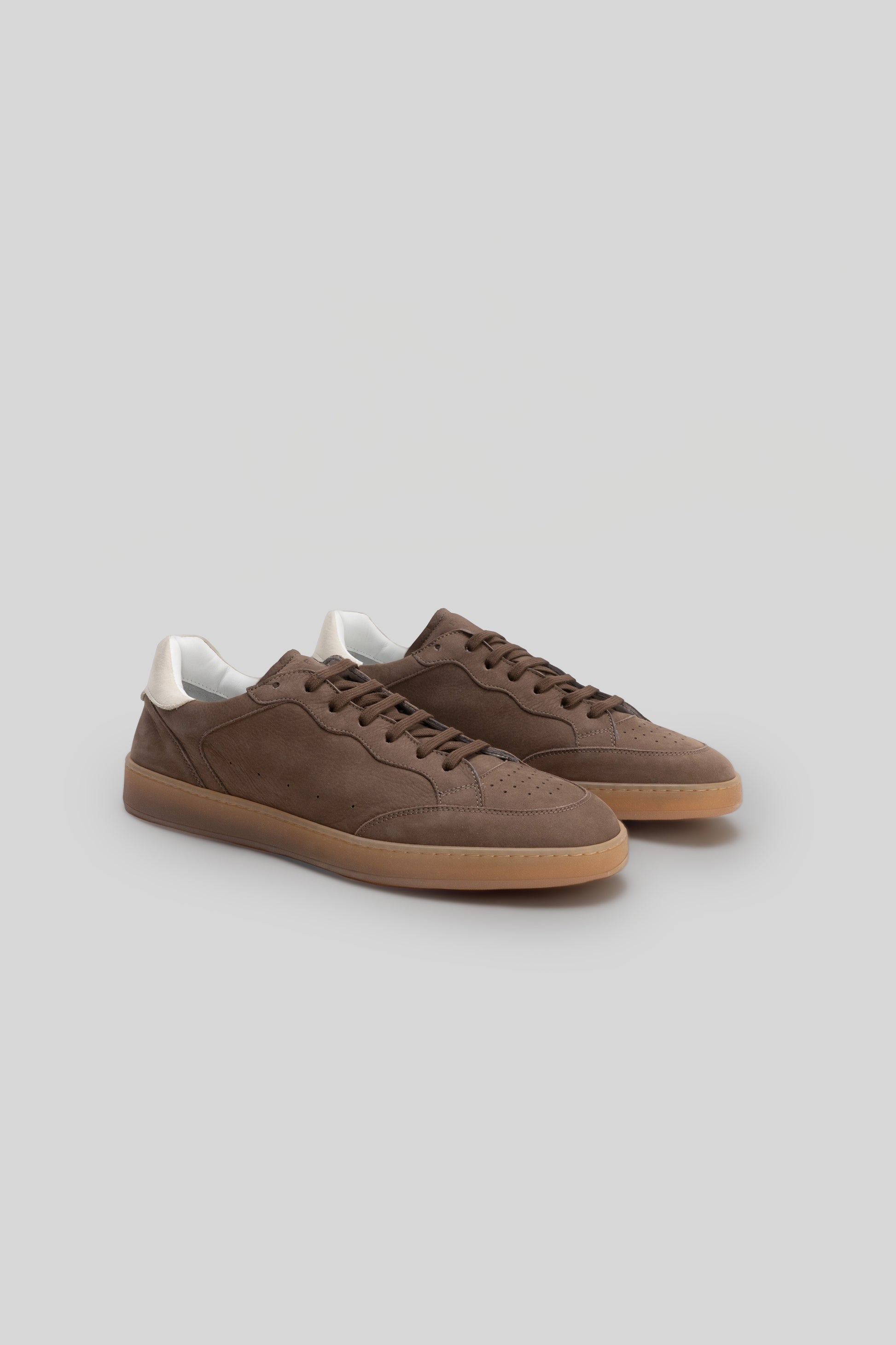 Brown suede sneakers with white collar trim and gum rubber sole, shown in three-quarter view.