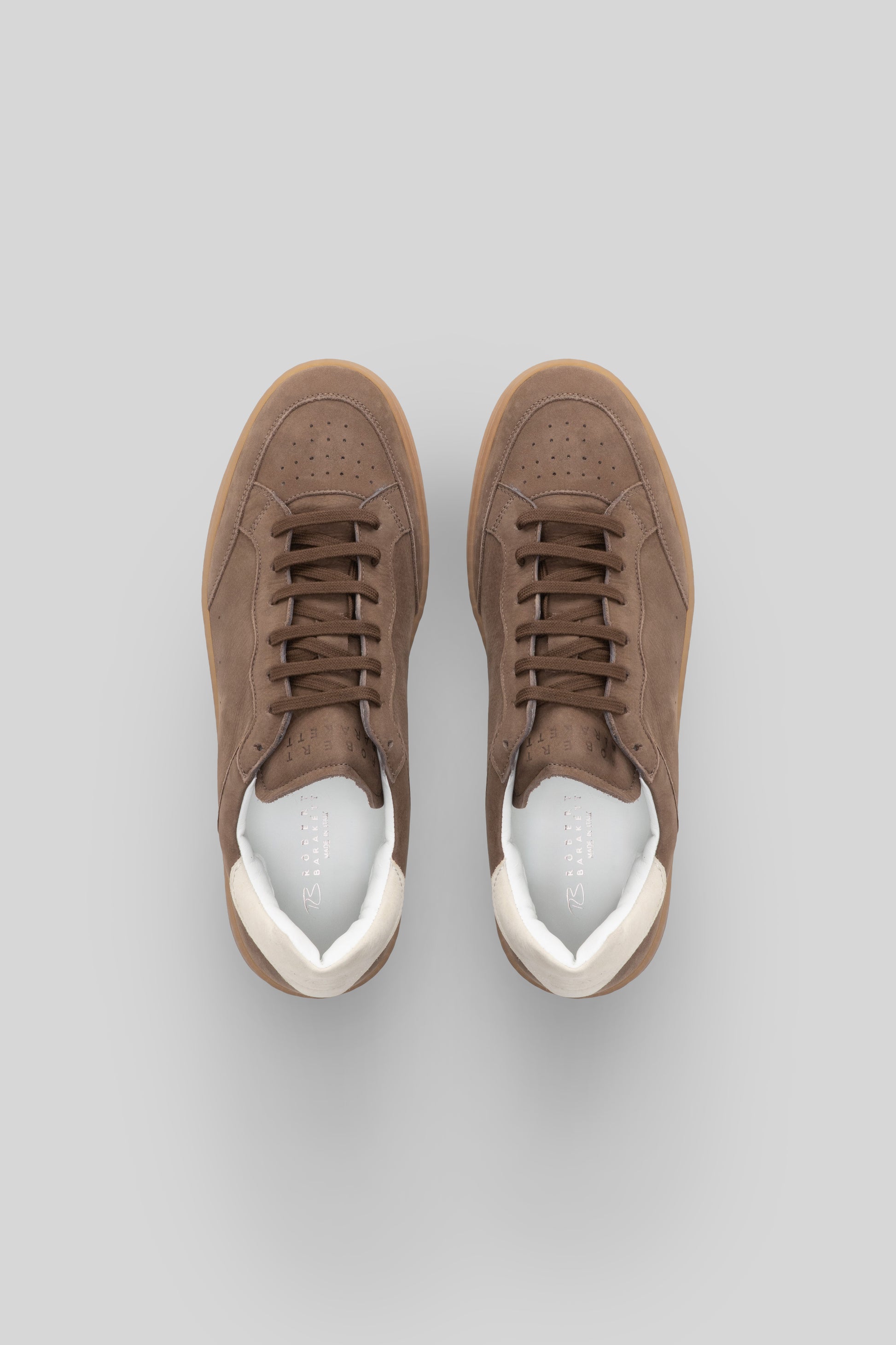 Pair of taupe suede court sneakers with white leather heel counter and gum sole, lace-up closure, top view.
