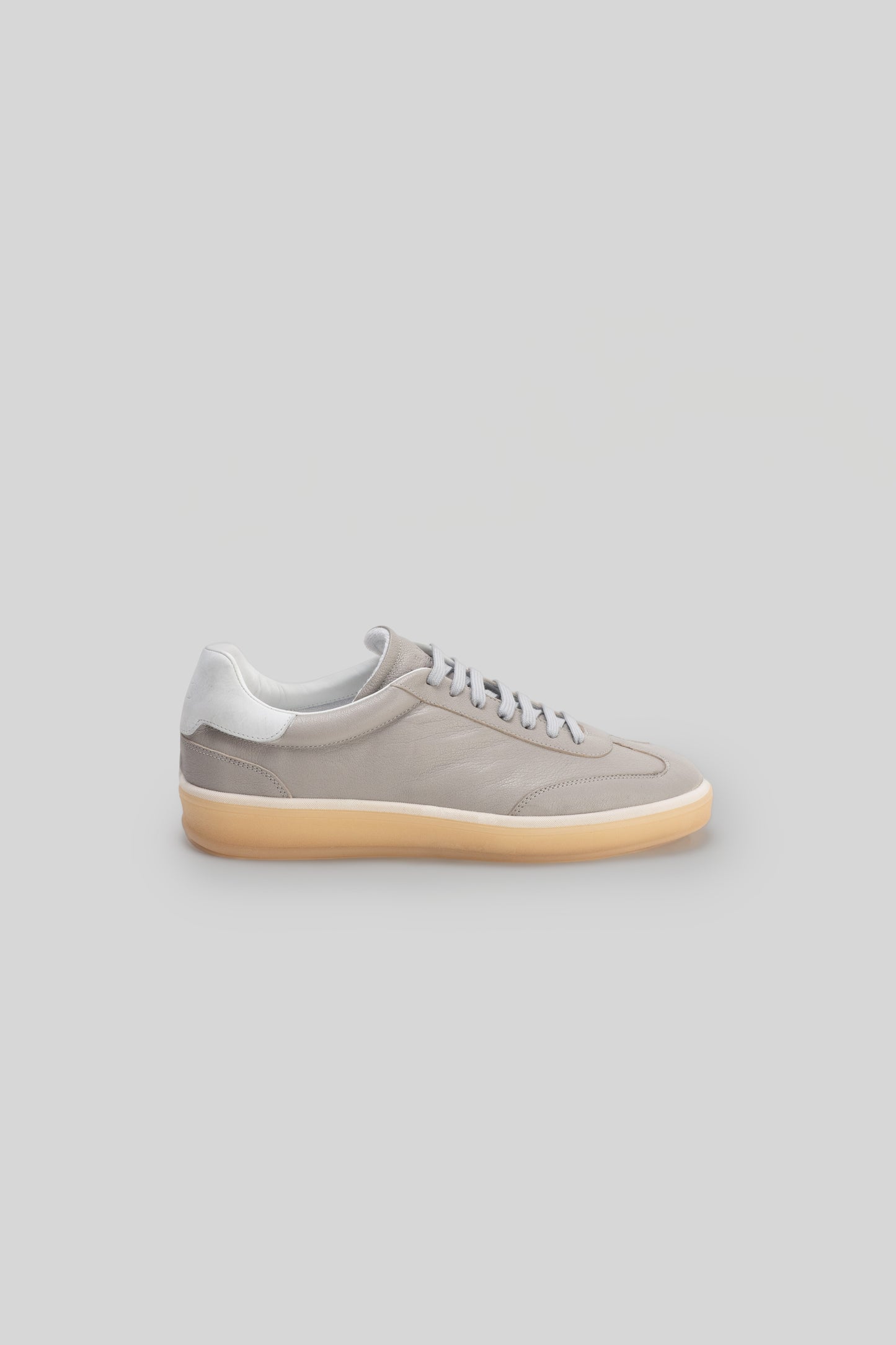 Beige and white leather sneaker with gum sole, shown in side profile against a neutral background.