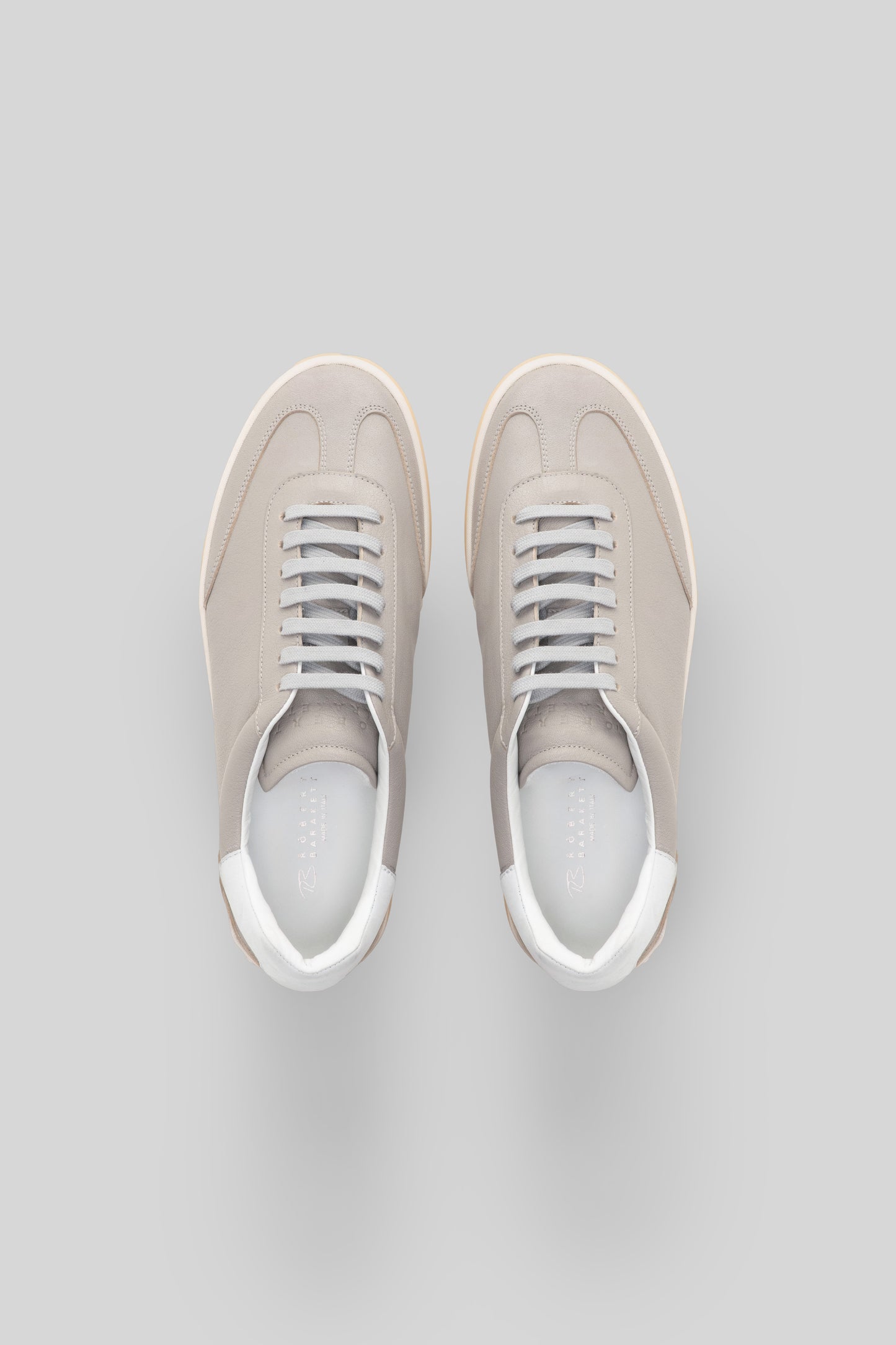 Pair of beige canvas sneakers with white laces and white rubber soles, shown from above.