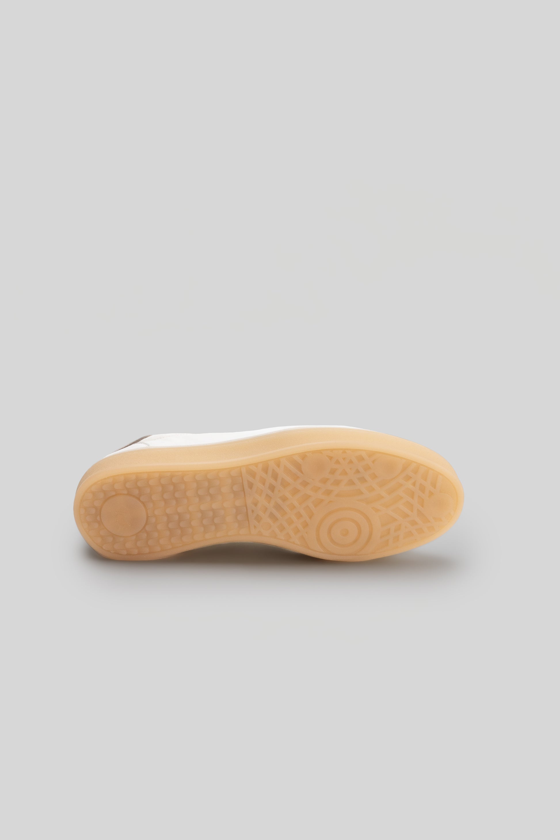 White sneaker sole with tan rubber tread and textured pattern detail.