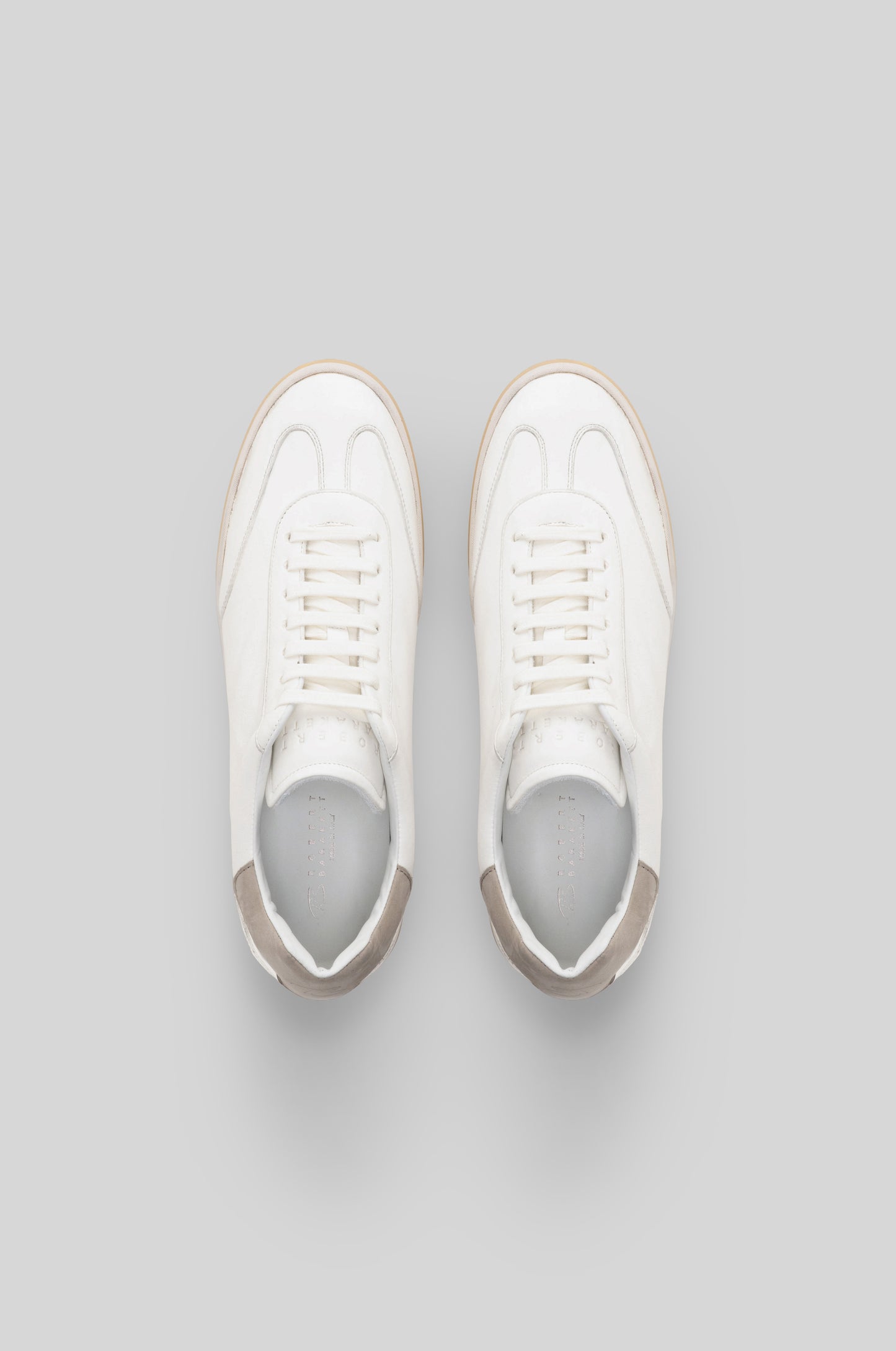 White leather sneakers with beige trim and white laces, shown from above.