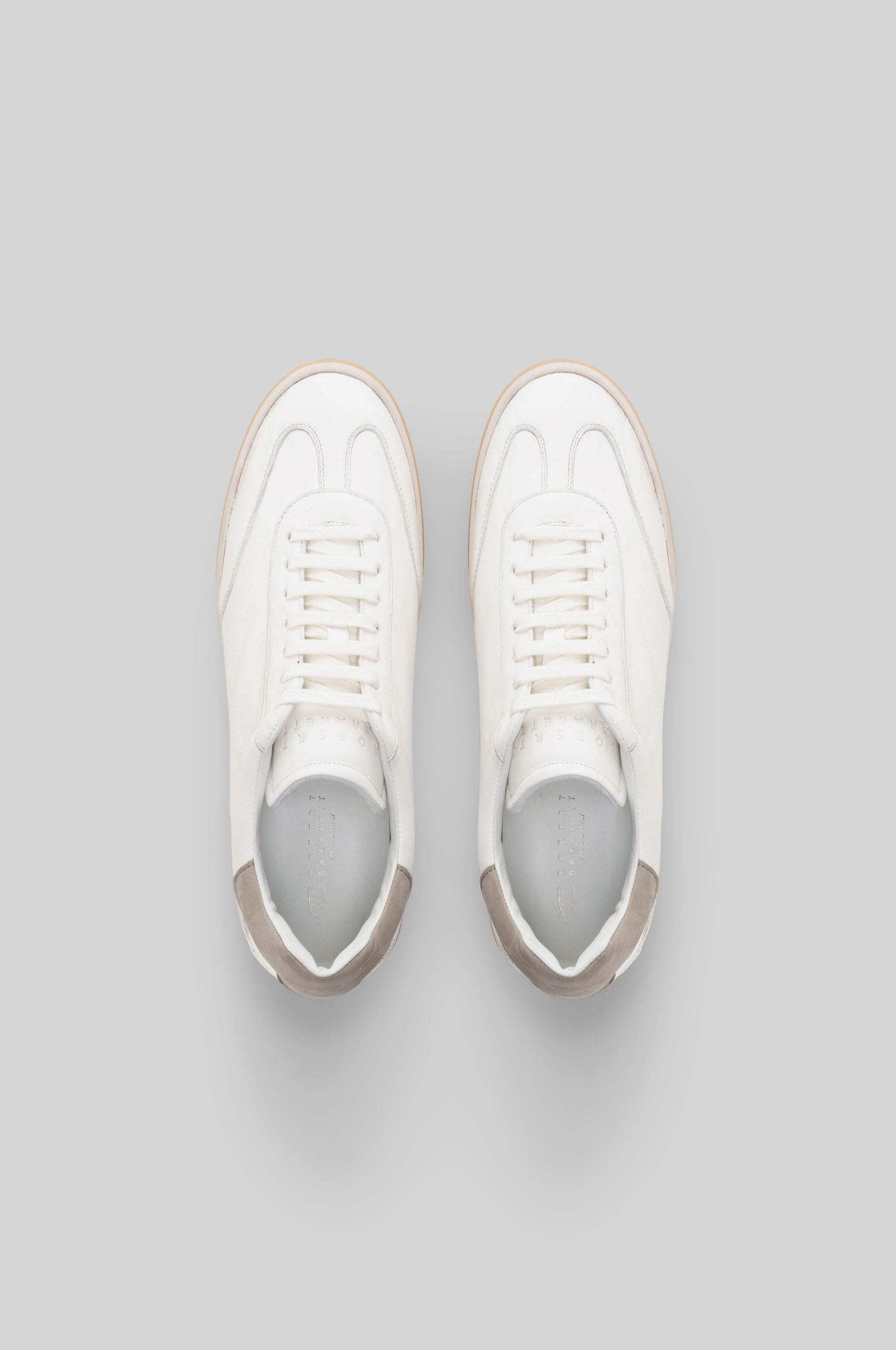 White leather sneakers with beige trim and white laces, shown from above.