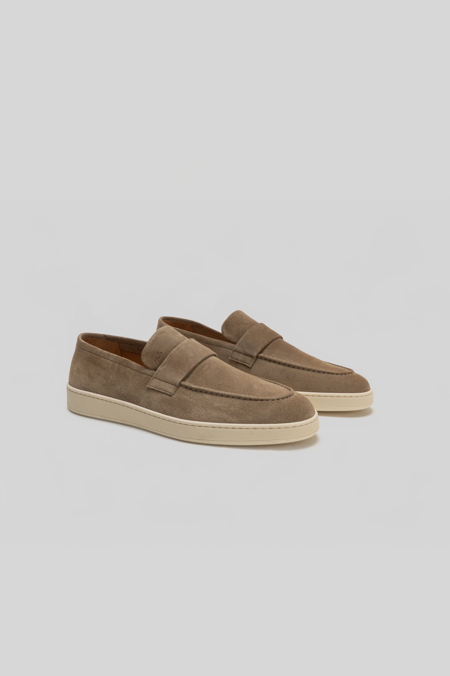 Pair of tan suede loafers with cream-colored rubber sole and stitched penny slot detail on upper.