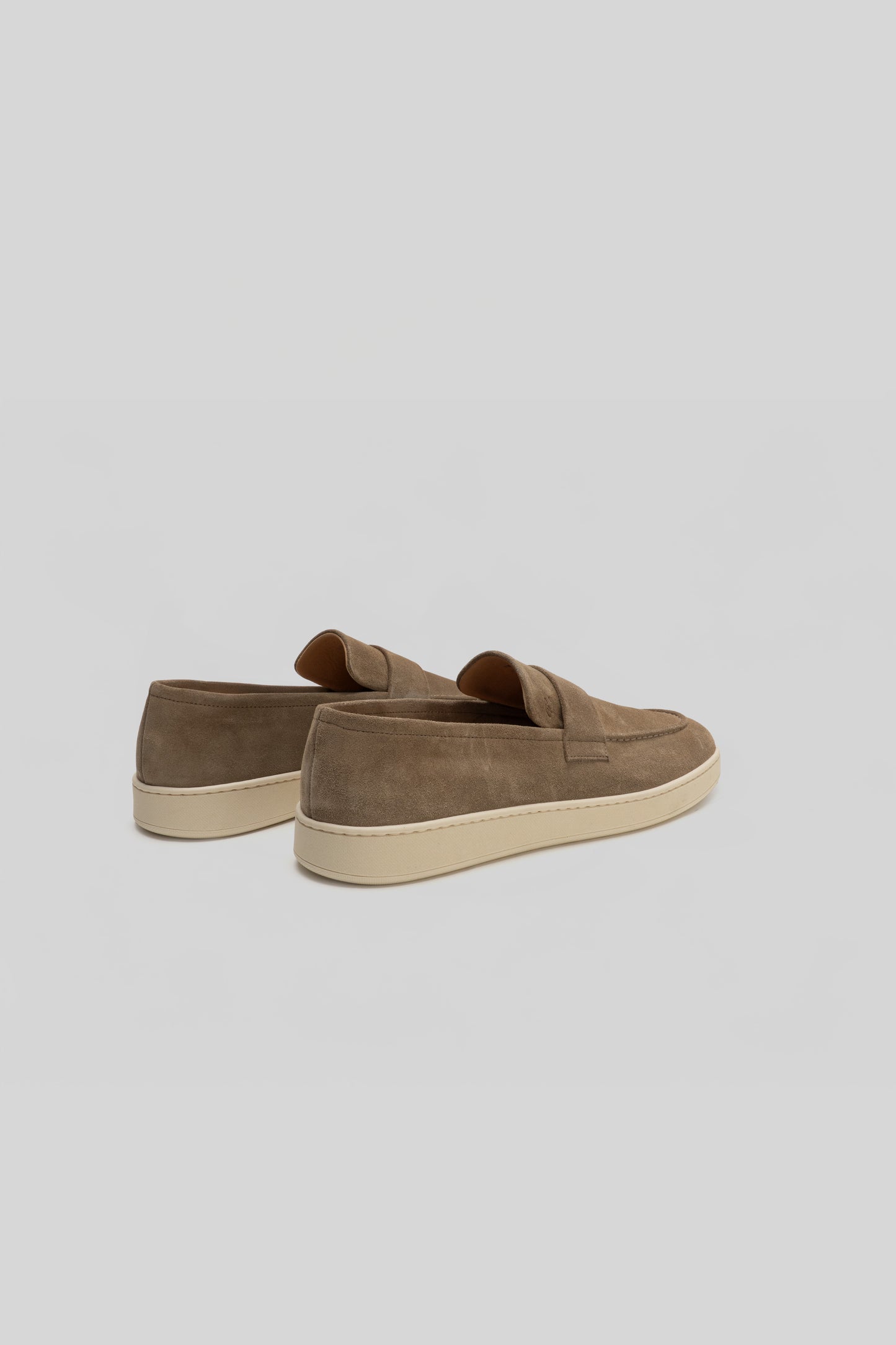 Pair of tan suede loafers with cream rubber soles, shown from the back angle.