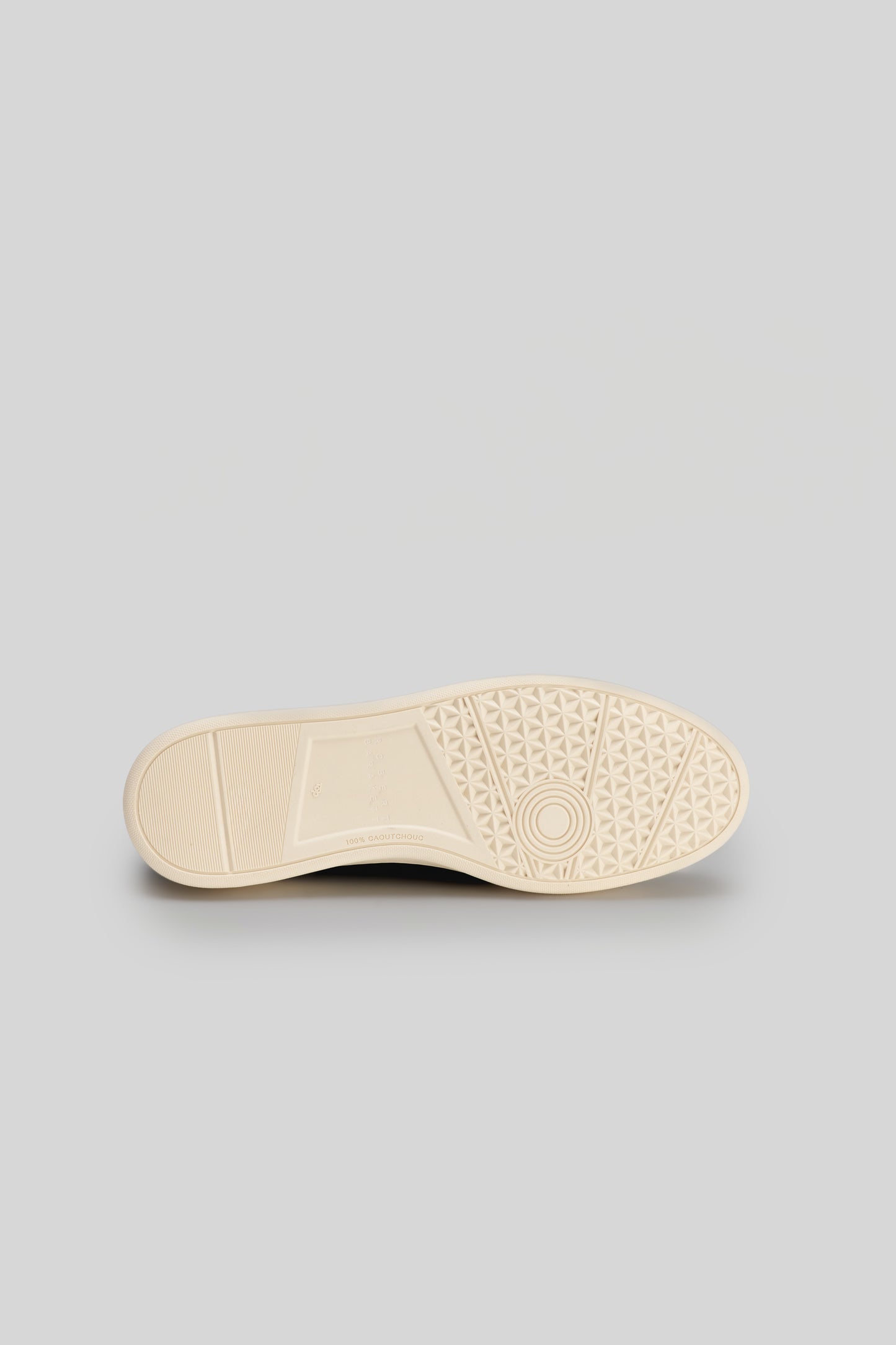 Cream-colored shoe sole with geometric tread pattern and circular center design.