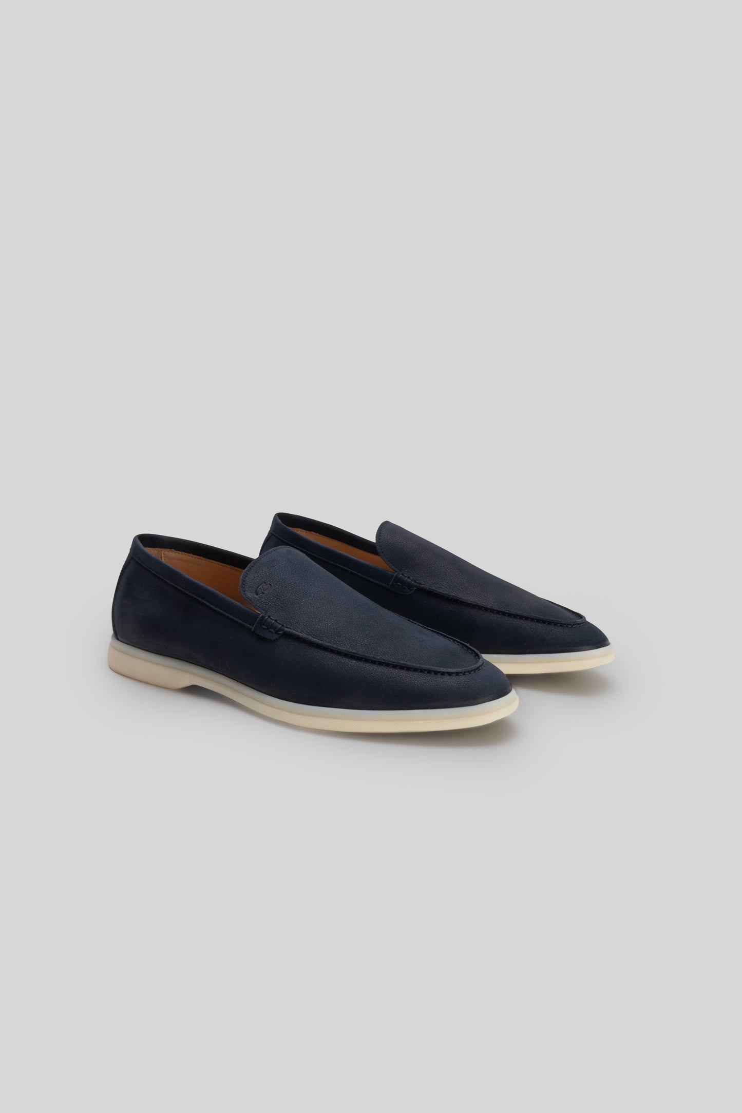 Navy blue loafers with cream rubber sole and brown leather interior lining.