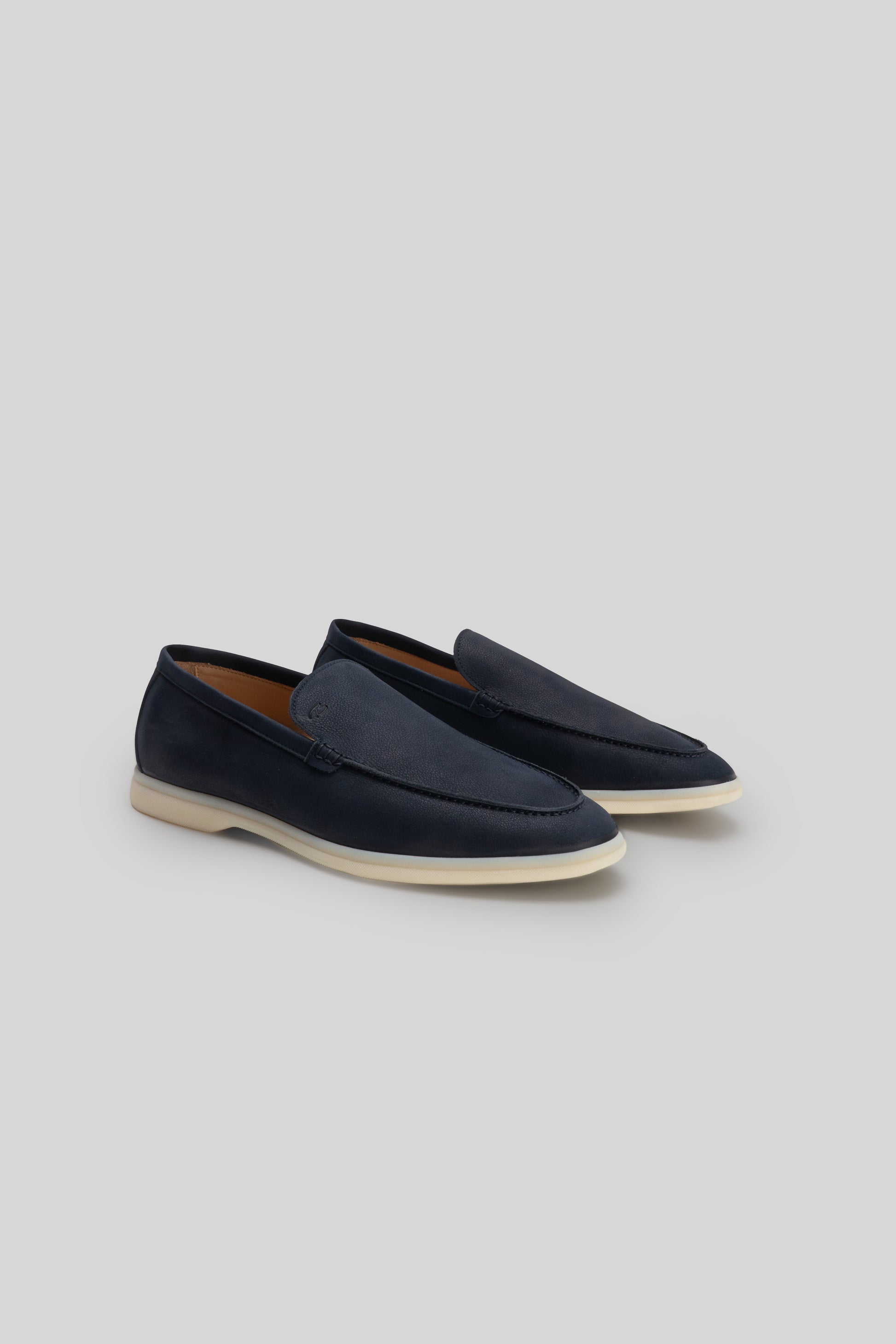Navy blue loafers with cream rubber sole and brown leather interior lining.