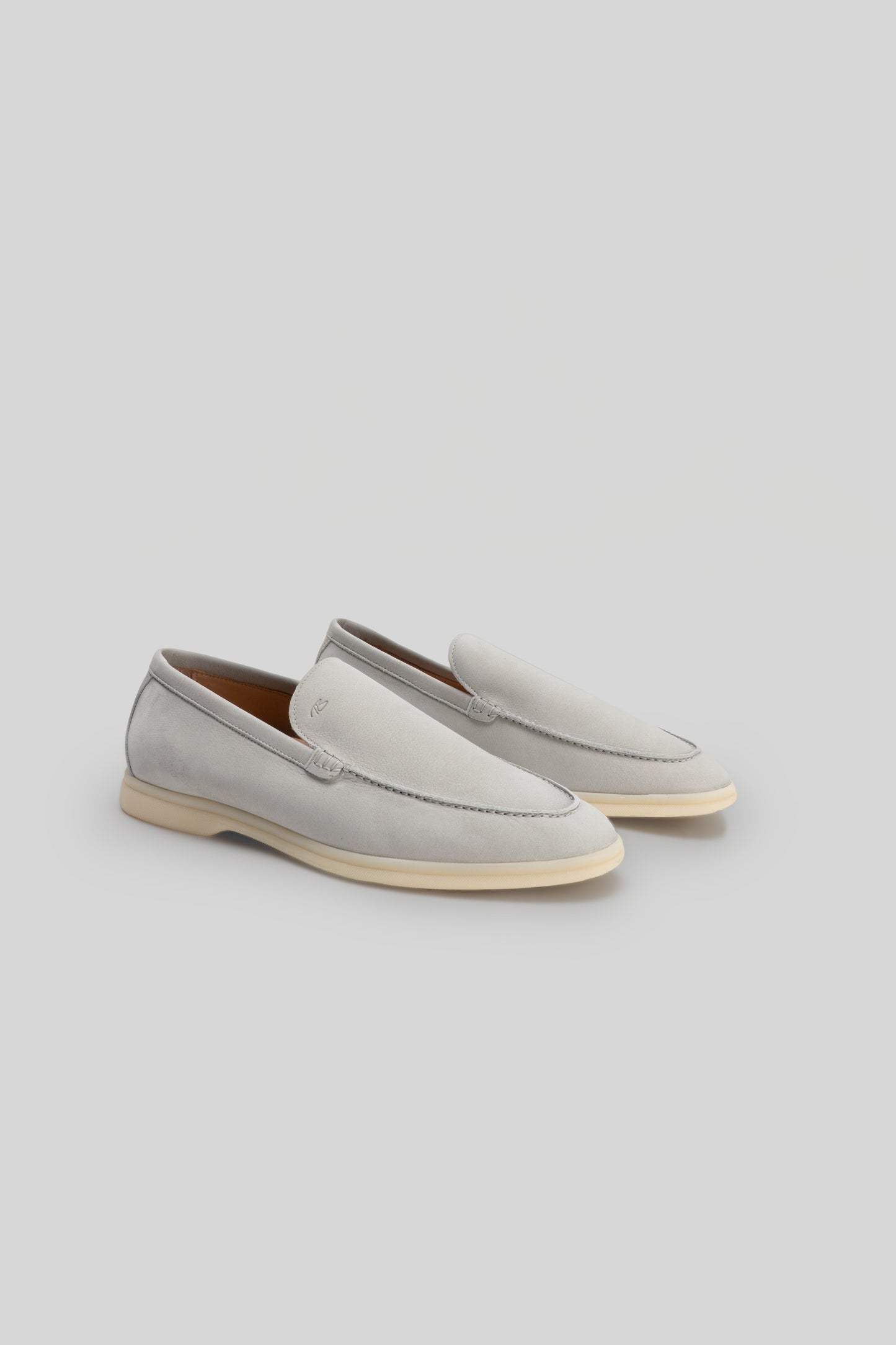 Pair of light gray suede loafers with cream-colored rubber soles, shown from a three-quarter angle.
