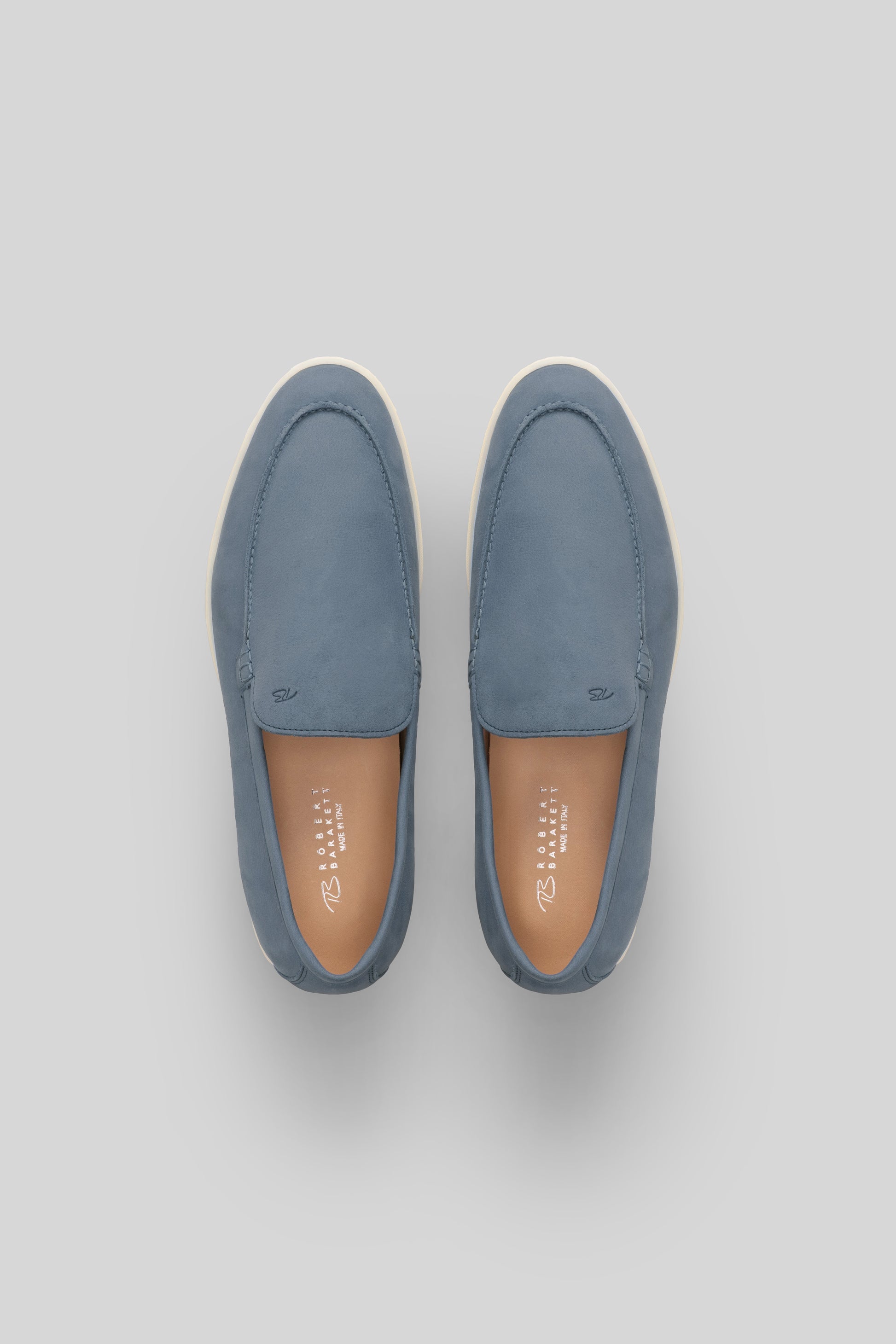 Pair of blue suede loafers with cream soles and tan leather insoles, shown from above.