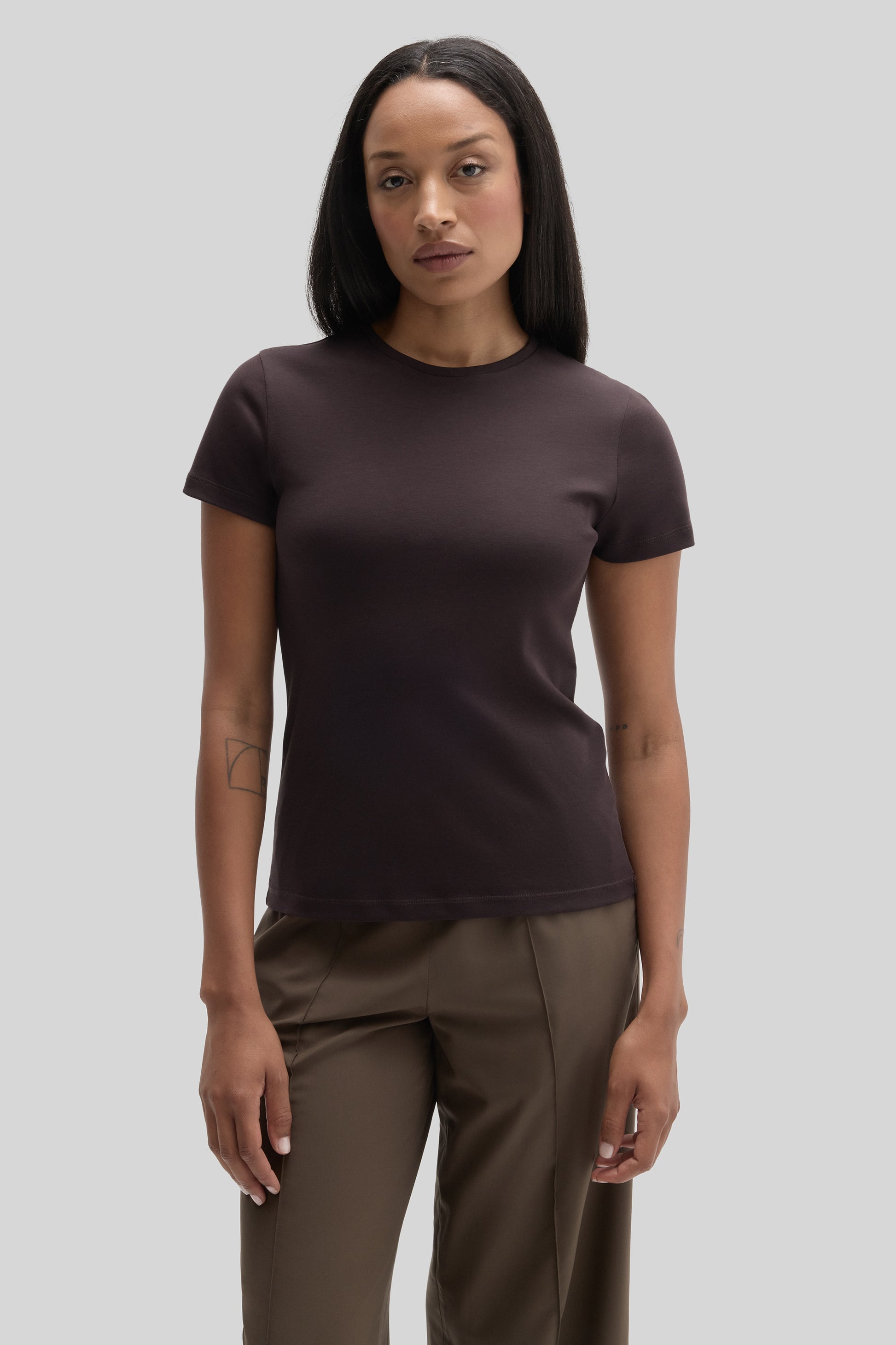 Woman wearing a dark brown crew neck t-shirt with short sleeves paired with olive-green pants.