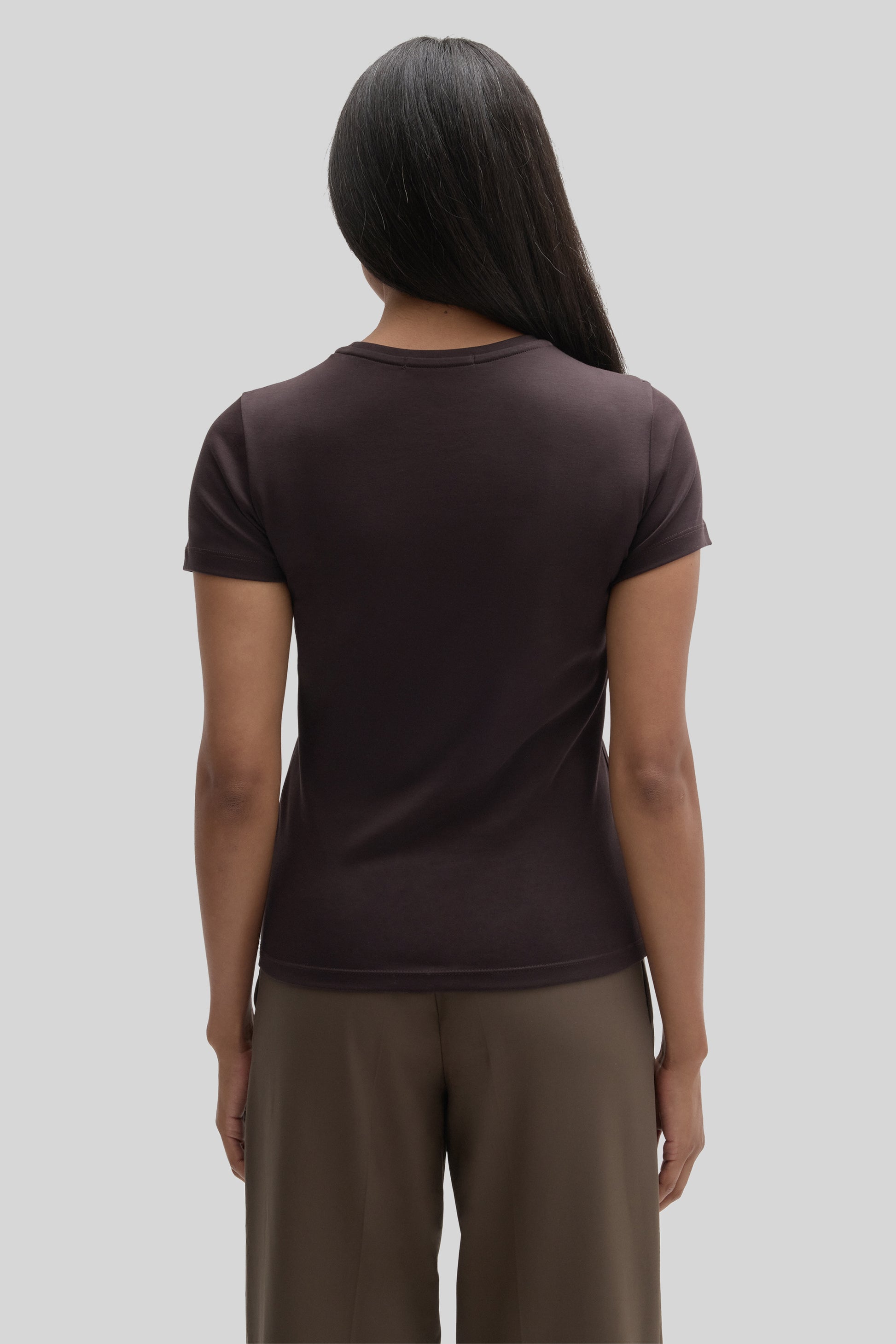 Woman wearing a dark brown short-sleeved crew neck t-shirt, shown from the back.