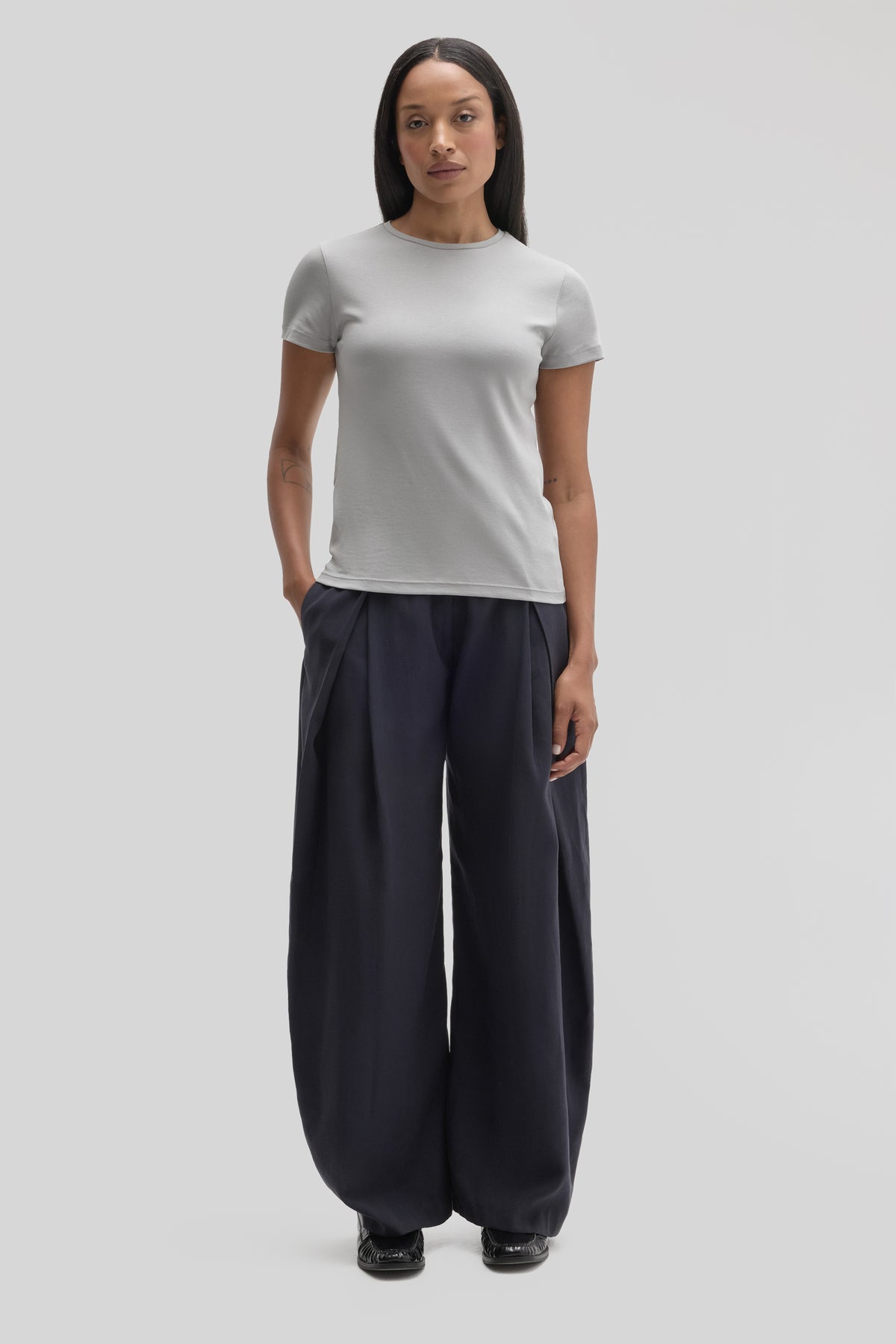 Woman wearing a white short-sleeve crewneck tee with black wide-leg pants and black shoes.
