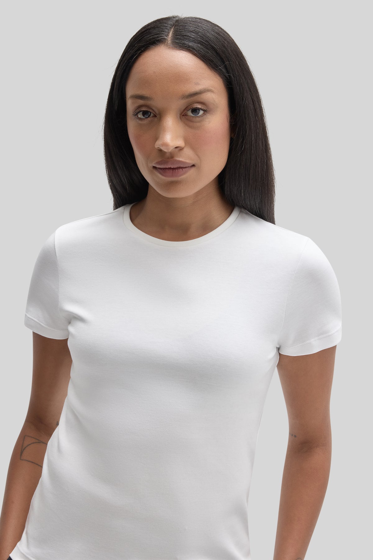 White short-sleeve crew neck t-shirt on a woman against a neutral background.